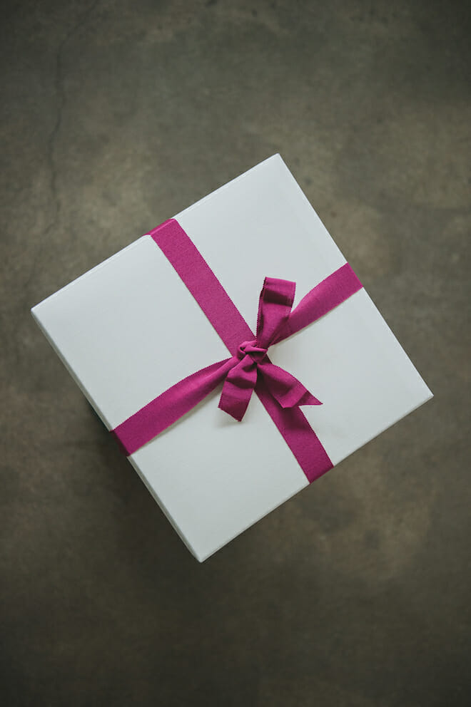 White gift box tied with a magenta ribbon on a dark background