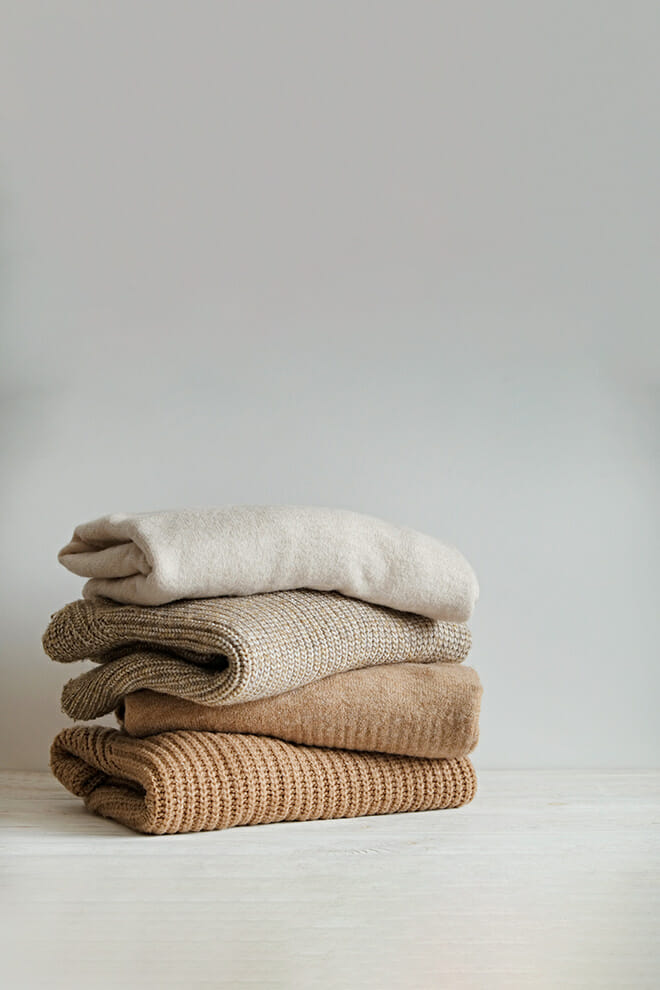 Stack of folded knitted wool sweaters in beige and brown tones