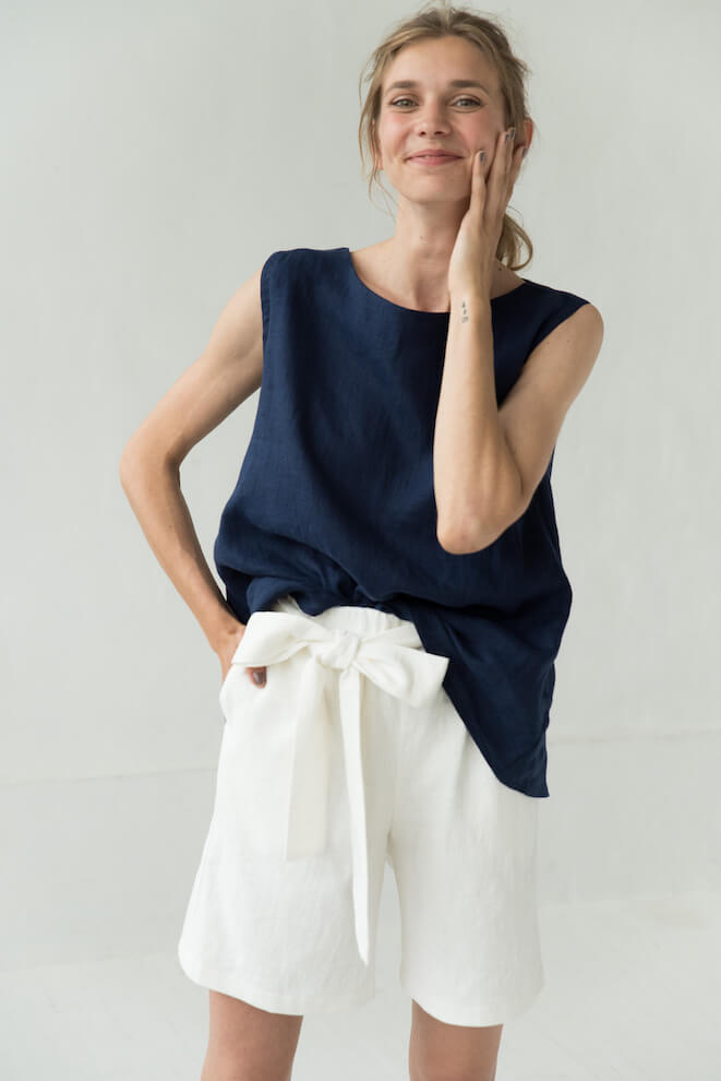Woman in a navy linen top and white linen shorts with a tie belt