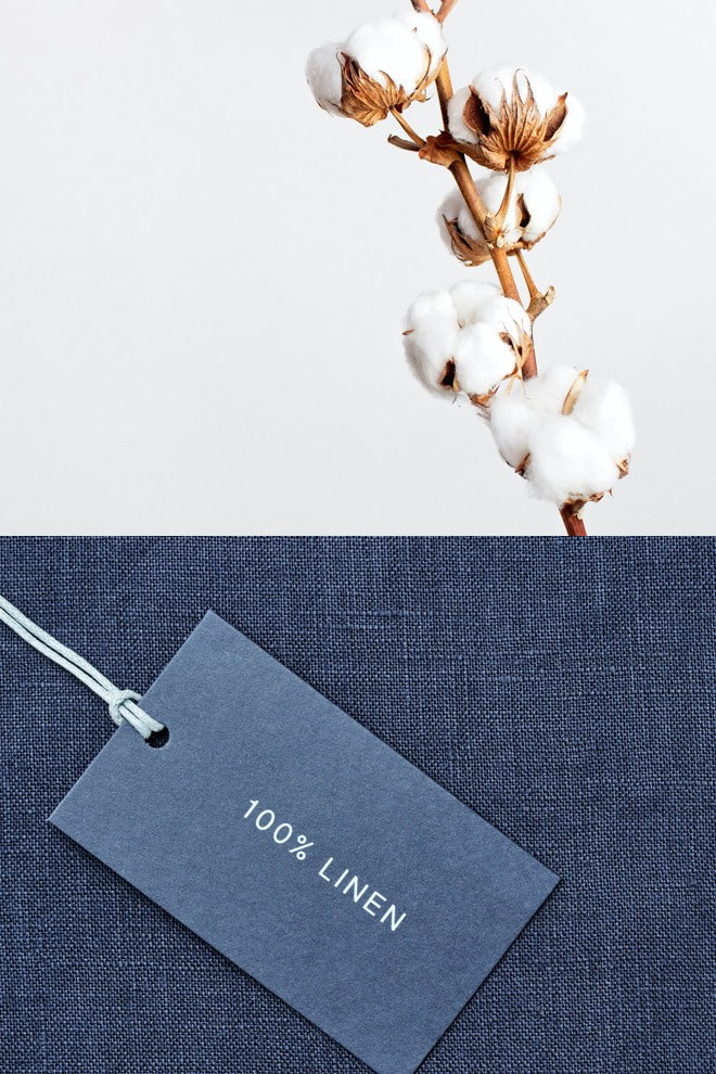 Cotton boll branch above navy linen fabric with a "100% linen" tag