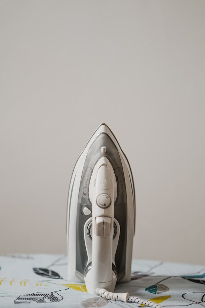Steam iron standing upright on an ironing board
