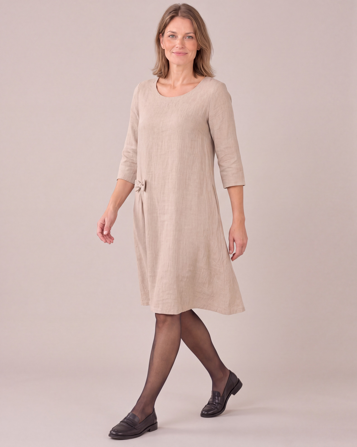 ADELE beige linen swing dress worn with tights and loafers, walking in the studio