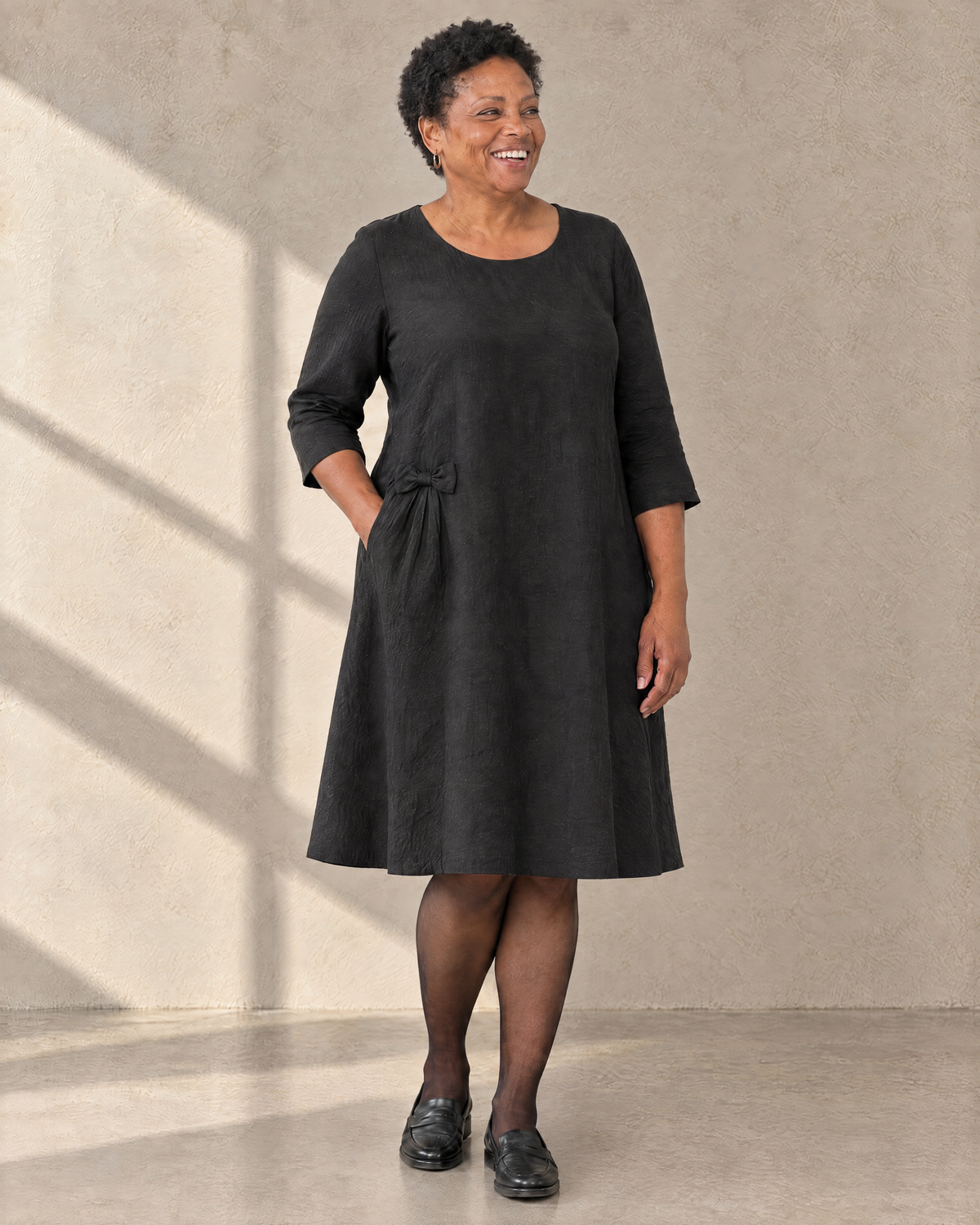 ADELE black linen swing dress with hip bow, three-quarter view