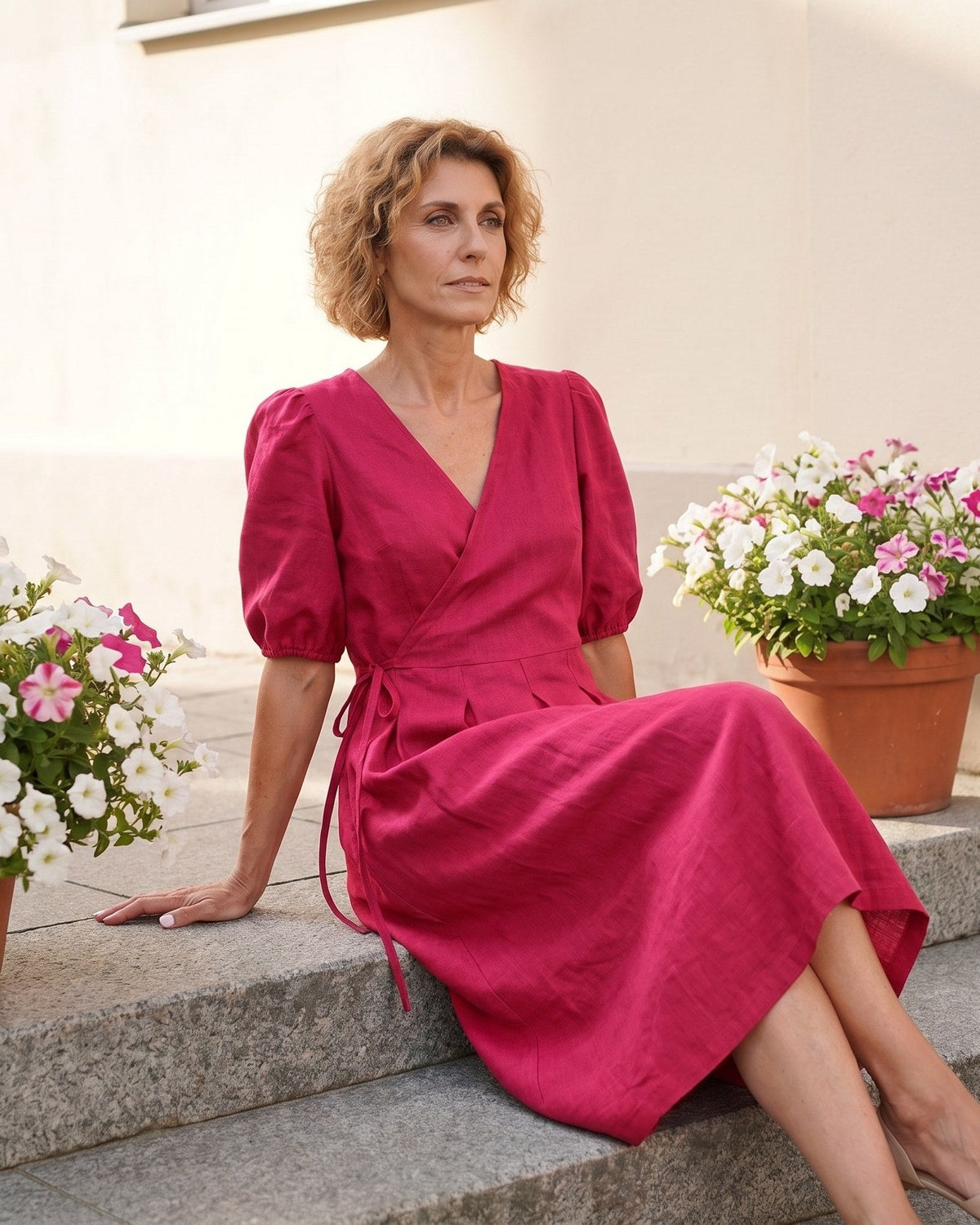 BONNIE – Linen Blend Puff Sleeve Tie-Waist Midi Dress – Cerise suknelė, lifestyle photo, seated outdoors among potted flowers #Color_Cerise