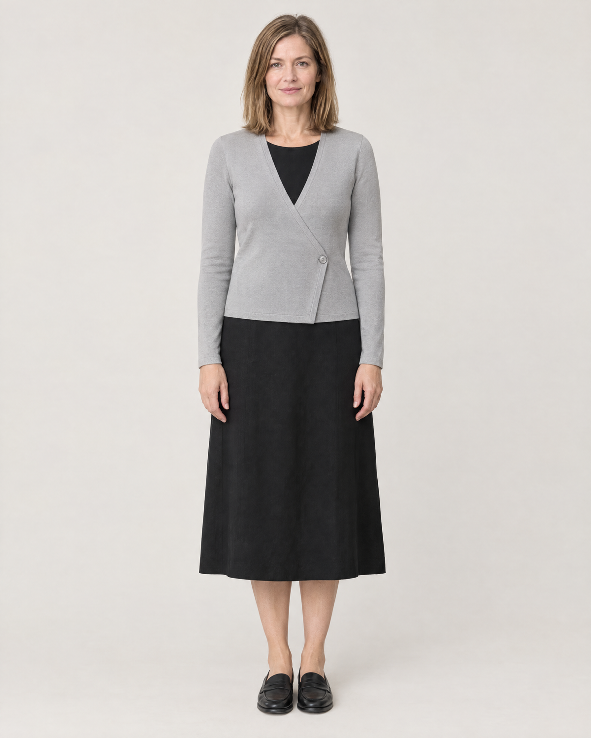 DRESS CARDIGAN light grey wool wrap cardigan over a black midi dress, front view with the single button at the waist