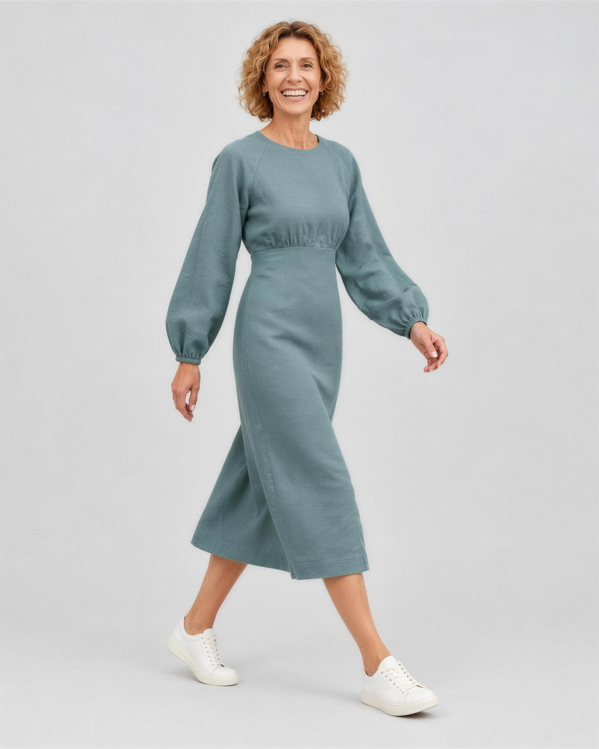 A woman walking, side view, wearing a muted dusty blue-green teal linen midi dress, showing how the linen fabric moves. #Color_Teal
