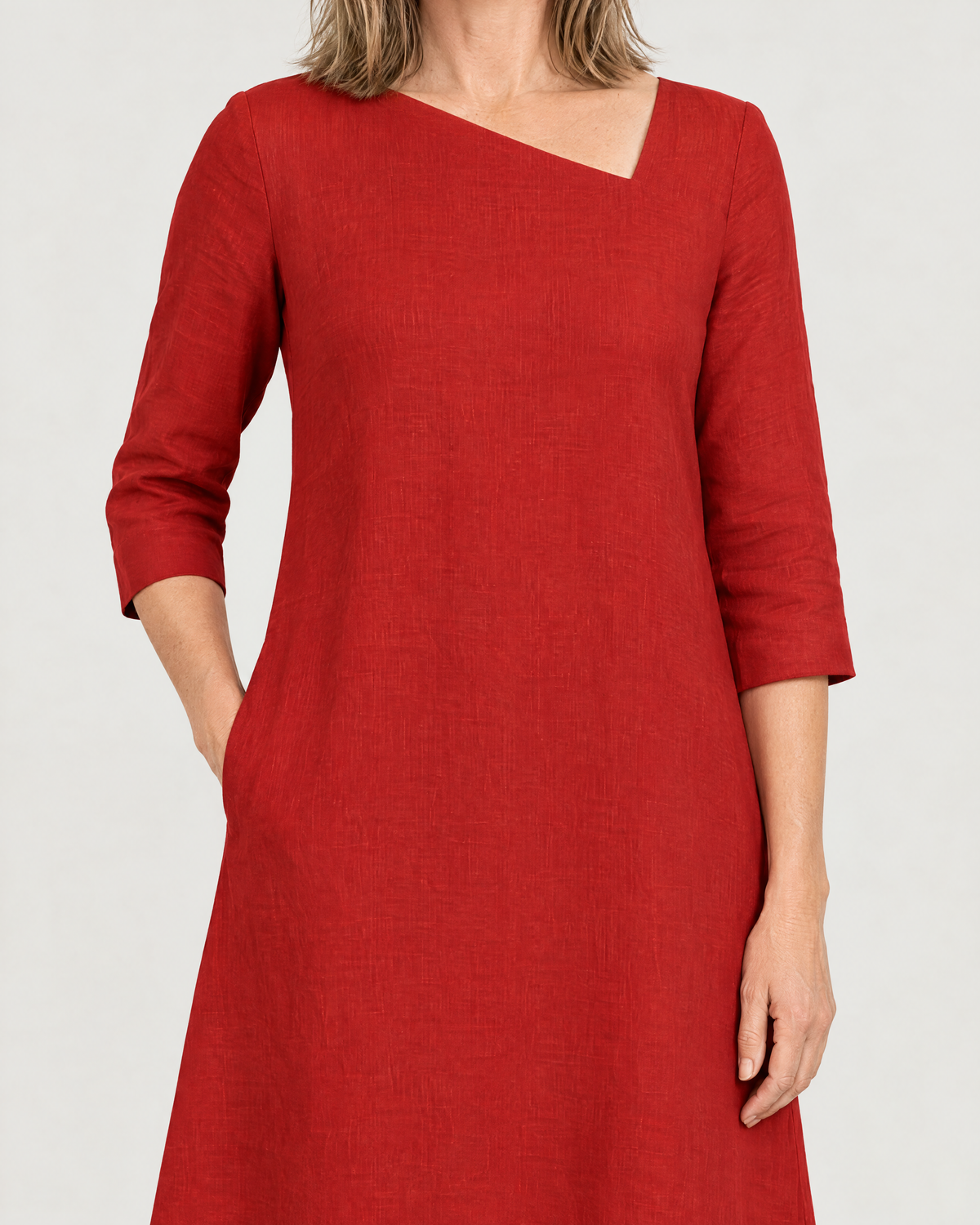 Close-up of the HUE asymmetric neckline, three-quarter sleeve and side pocket in red linen