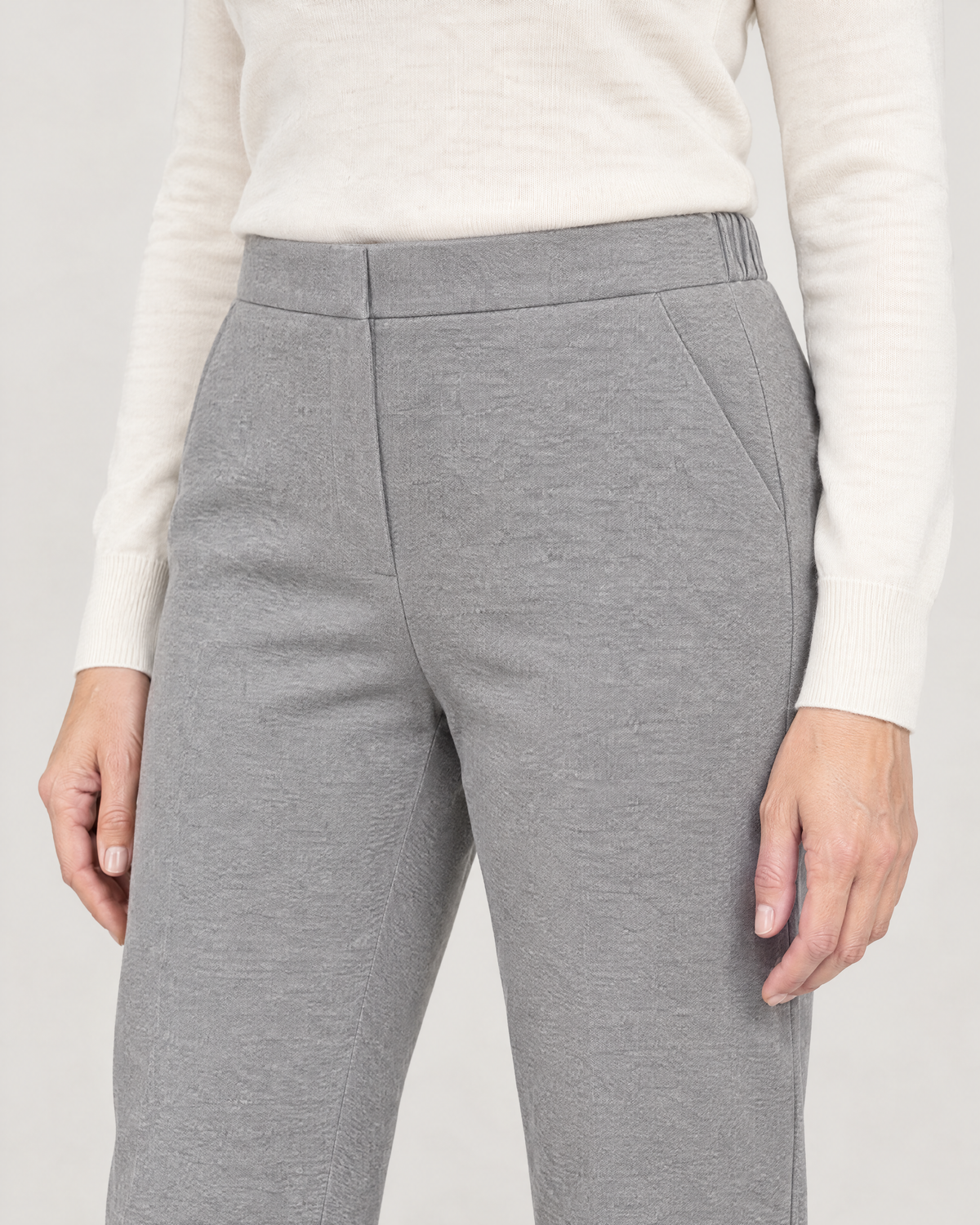 Close-up of the flat front waistband, concealed zip and slanted pocket in light grey wool knit