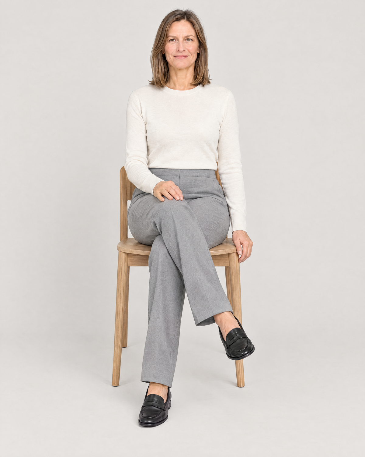 Woman seated in GRAPHITE COMFORT light grey trousers, the front waistband stays flat while sitting