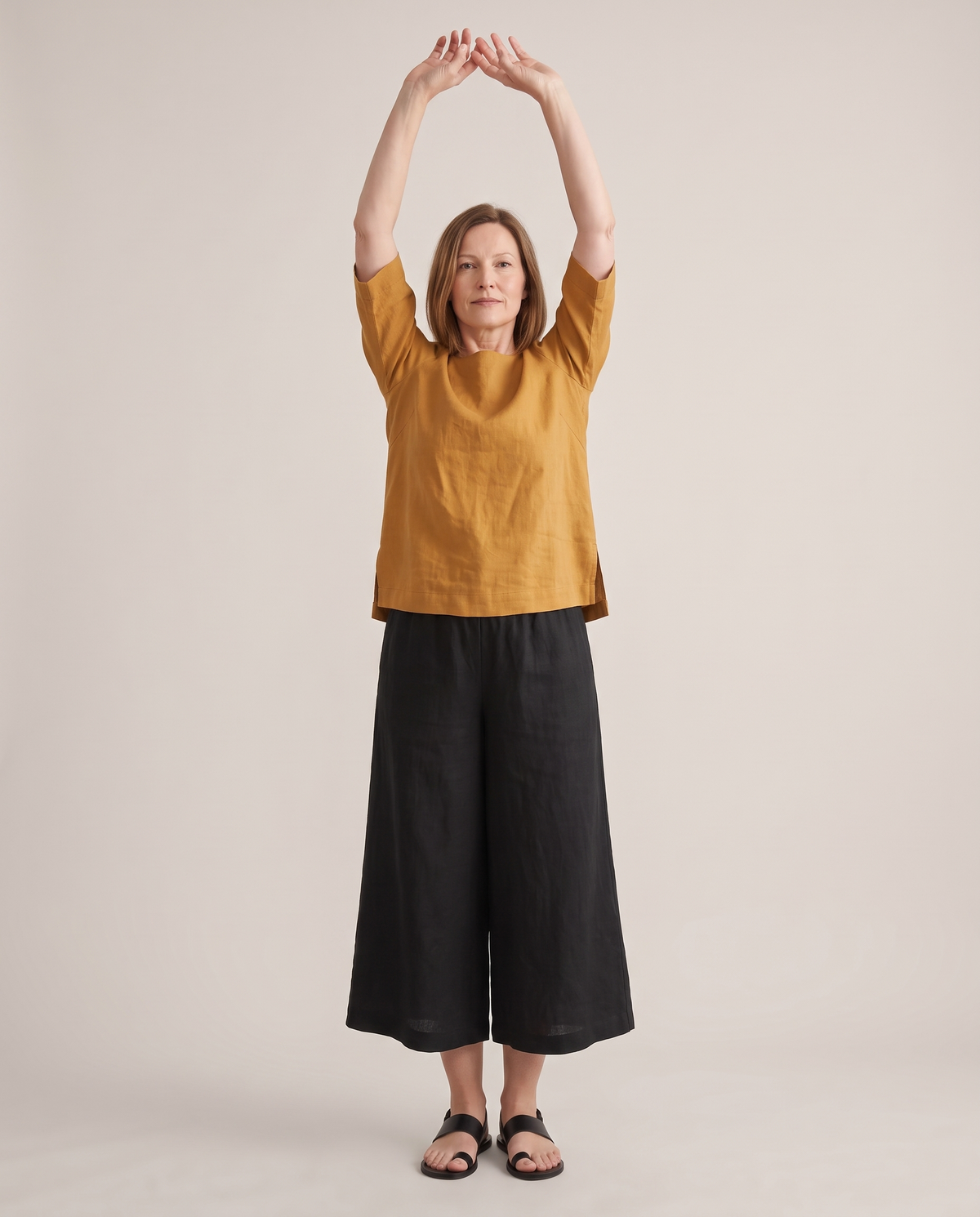 LIFT linen top in Ochre with both arms raised, hem stays in place
