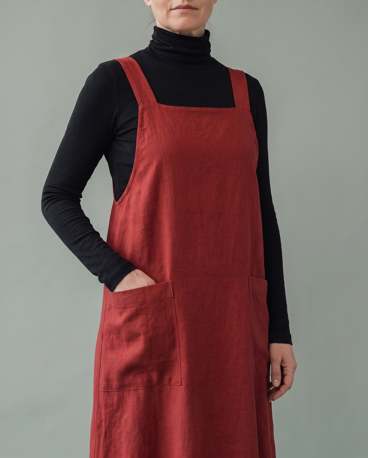 LAYER linen midi pinafore dress in Red worn over a black turtleneck