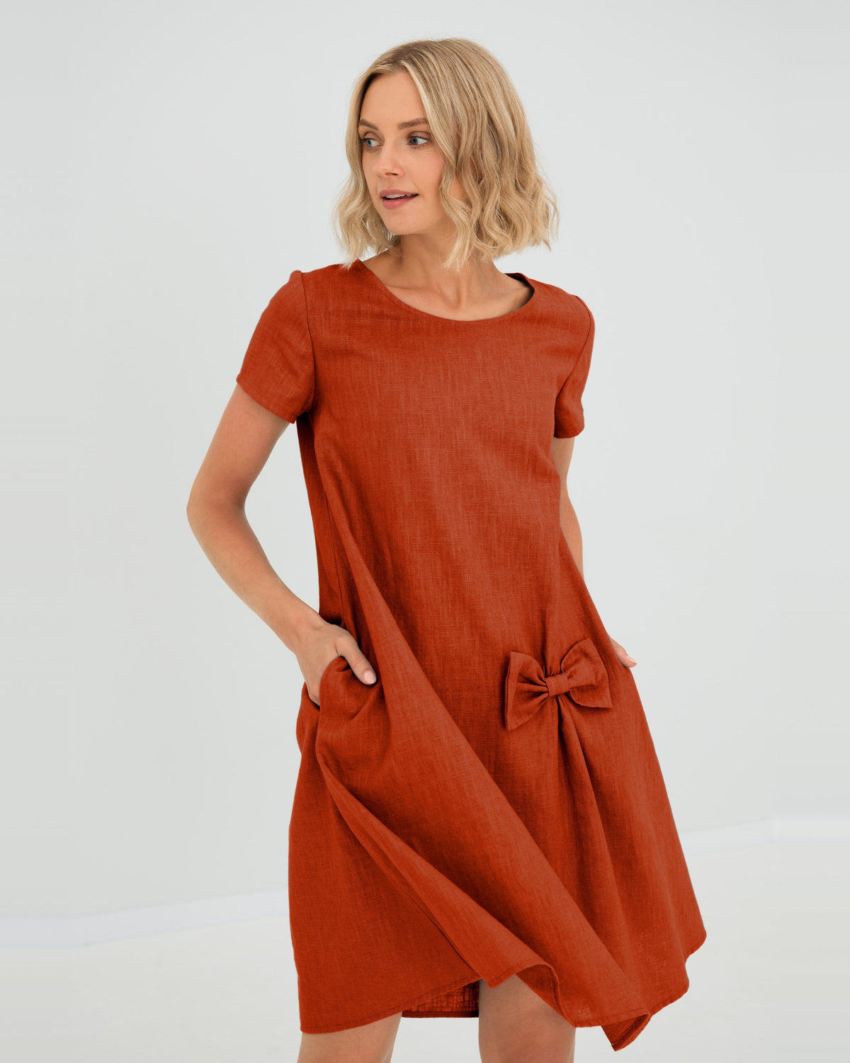 LeMuse SUMMER KISS linen dress in orange – studio front view, hand in pocket #Color_Orange