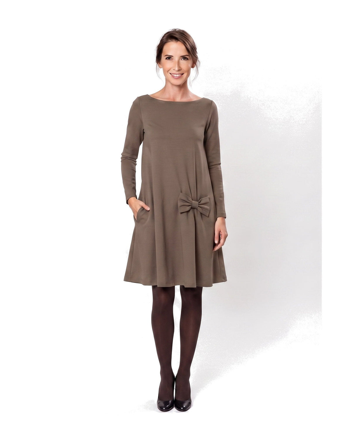 A woman modeling a brown long-sleeve A-line dress with a boat neckline, side pockets, and a bow detail at the waist. #Color_Brown