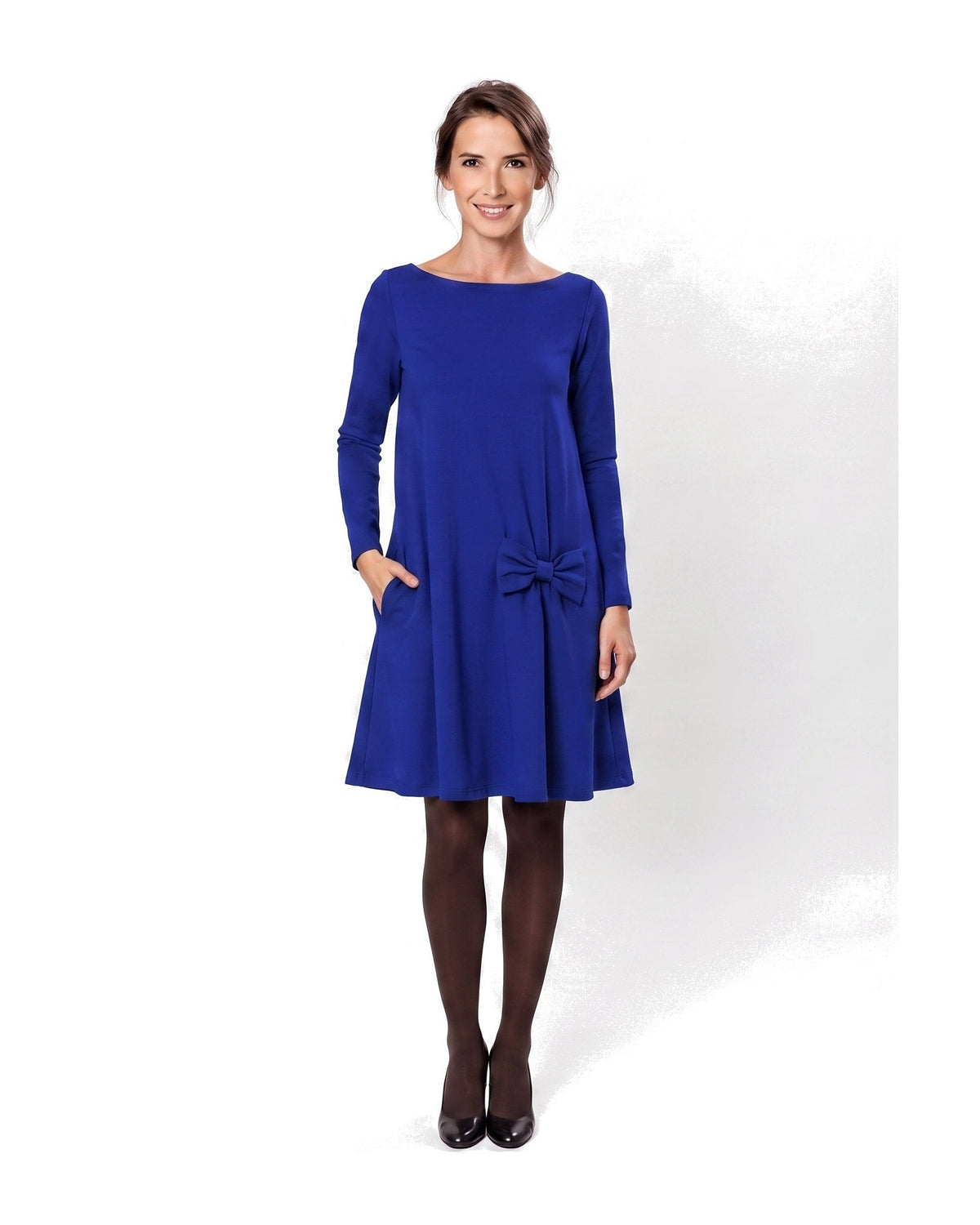 A woman modeling a sapphire blue long-sleeve A-line dress with a boat neckline, side pockets, and a bow detail at the waist. #Color_Sapphire blue
