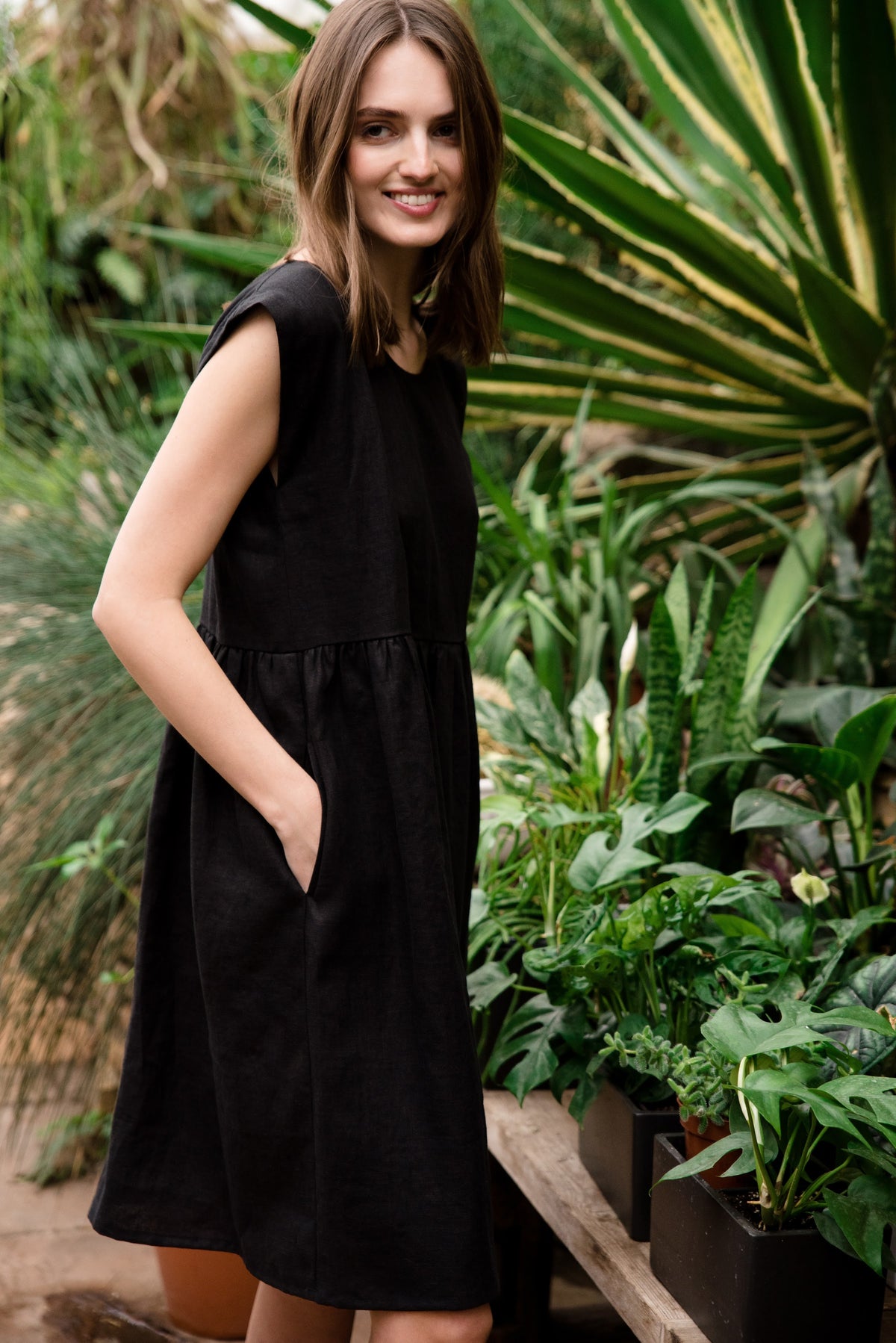 LeMuse LUNA linen dress in black – 3/4 view, hand in pocket #Color_Black