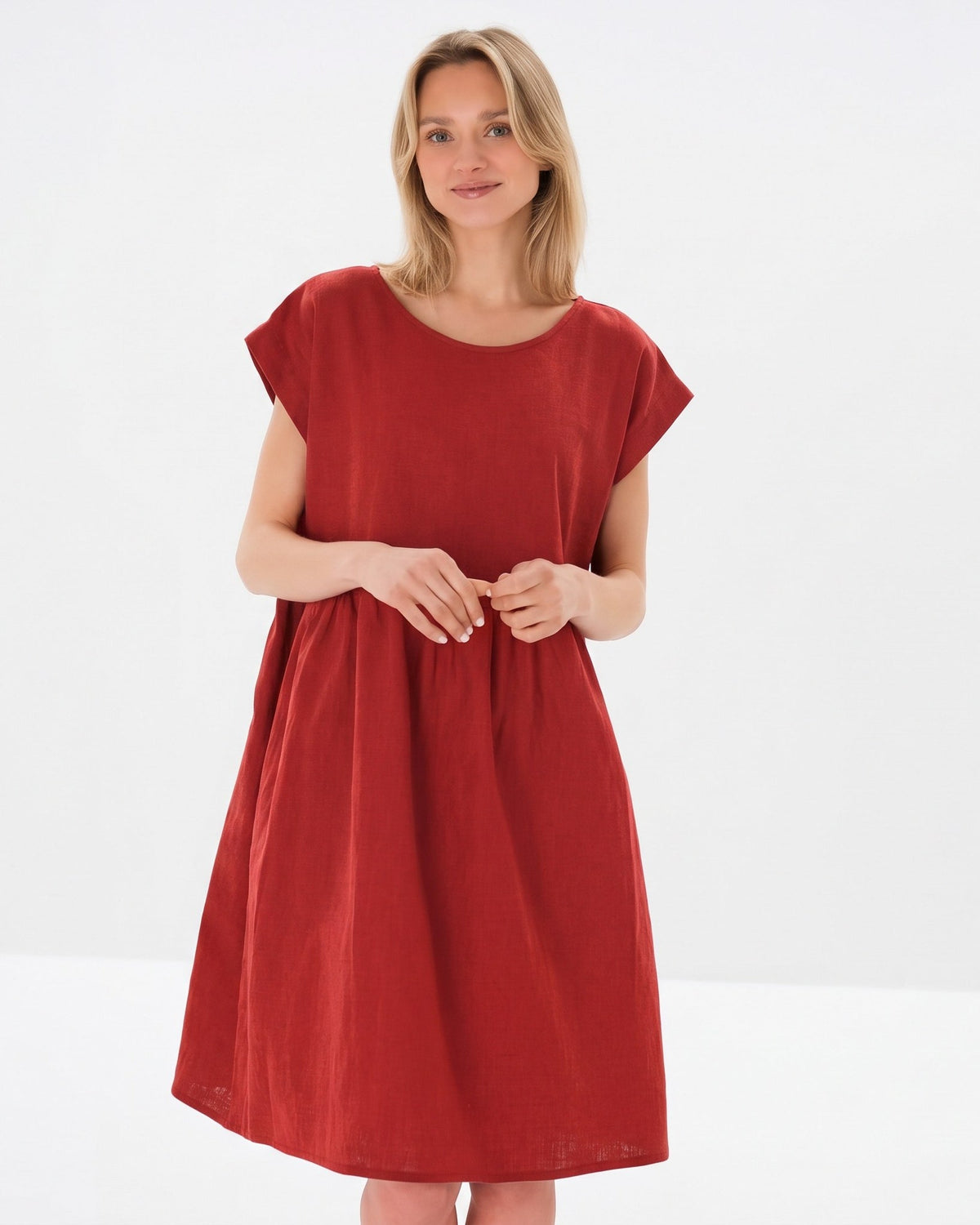 Kvinna visar en löst sittande, kortärmad röd klänning mot en ren vit studiobakgrund. #Color_Red