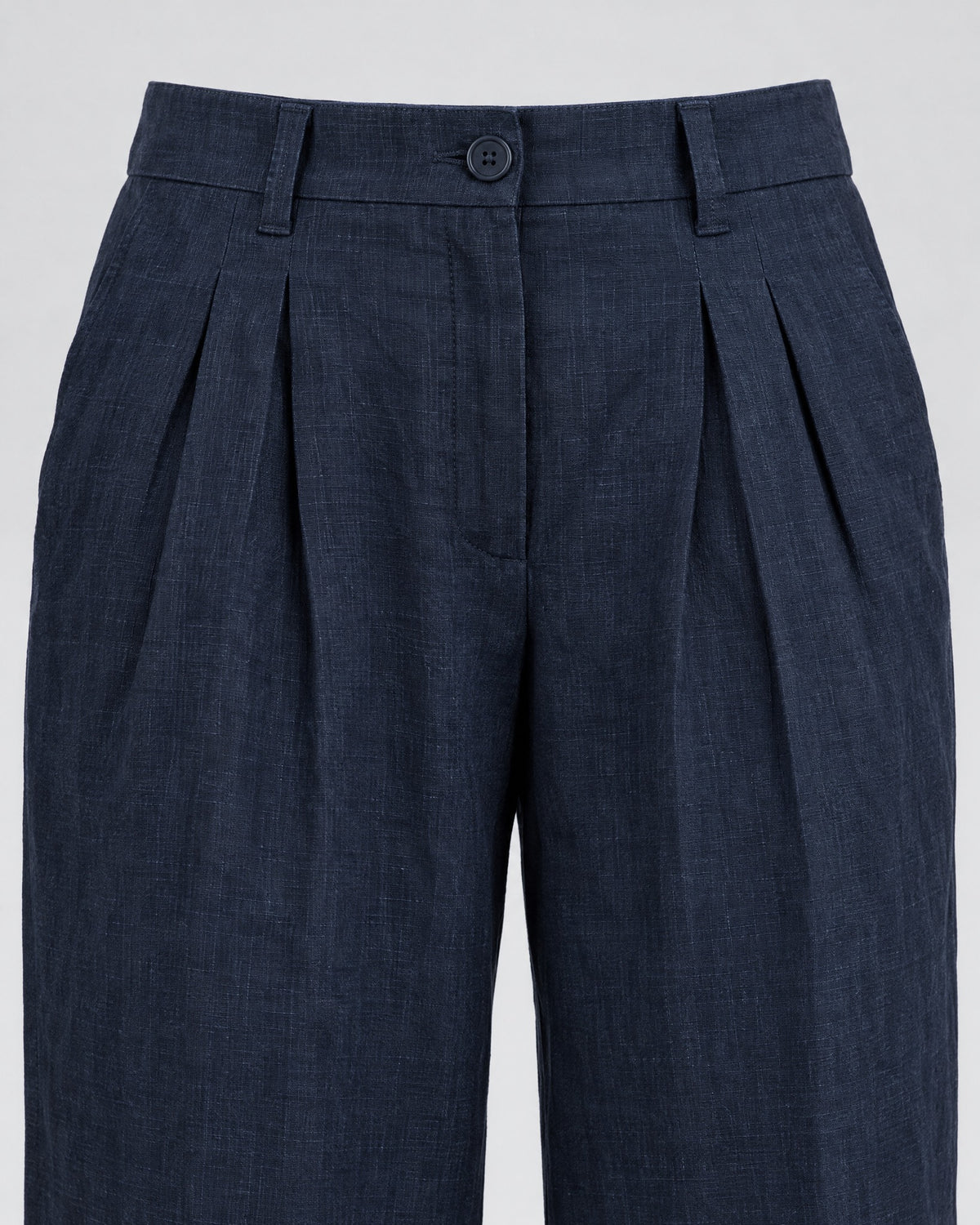 Close-up of deep navy blue wide-leg linen trousers showing the waistband, front pleats and button closure. #Color_Deep blue