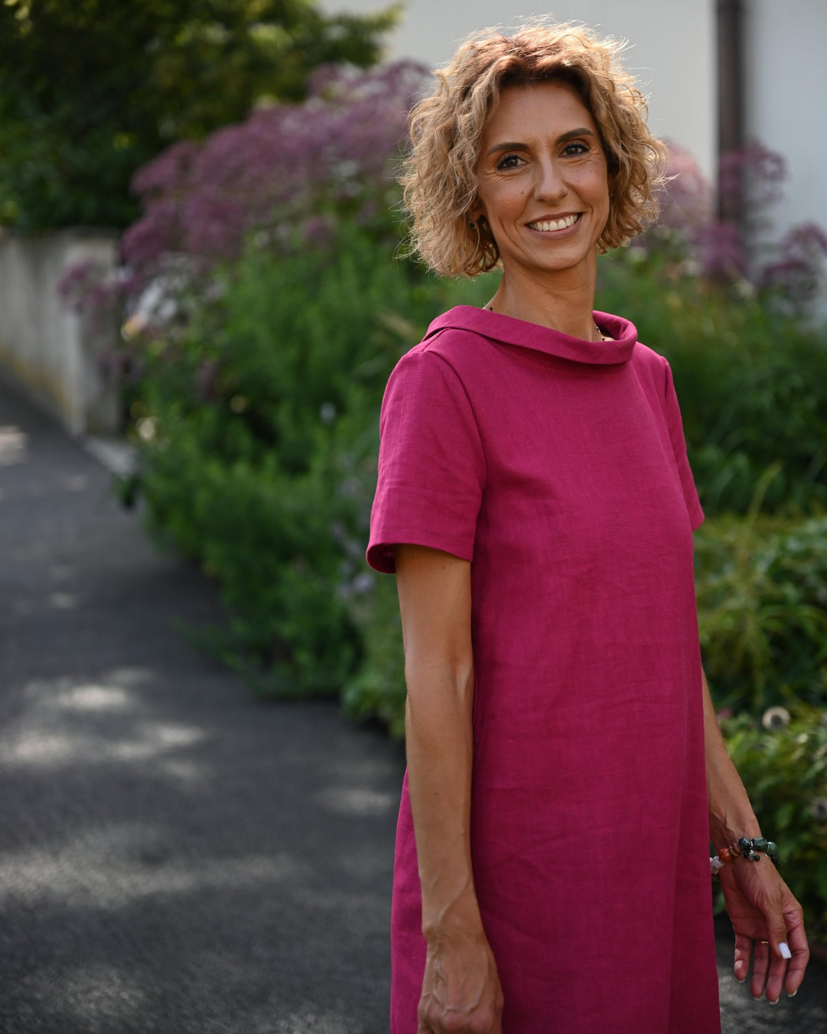 LeMuse STORY linen dress in cerise – front view in garden, cropped at mid-thigh #Color_Cerise