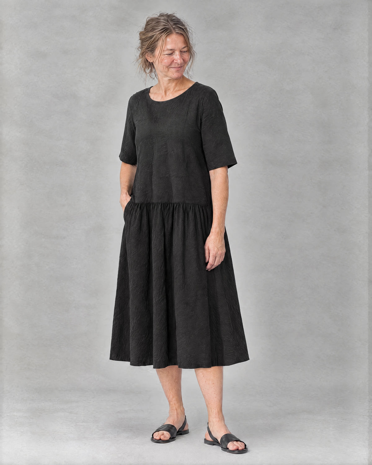TESSA black linen tiered midi dress, three-quarter view of the dropped waist and gathered tier