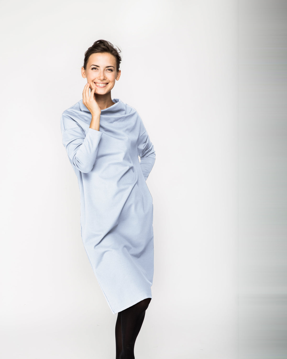 A woman wearing a light blue long-sleeve cowl-neck midi dress with side pockets, standing against a white background, front view. #Color_Sky blue