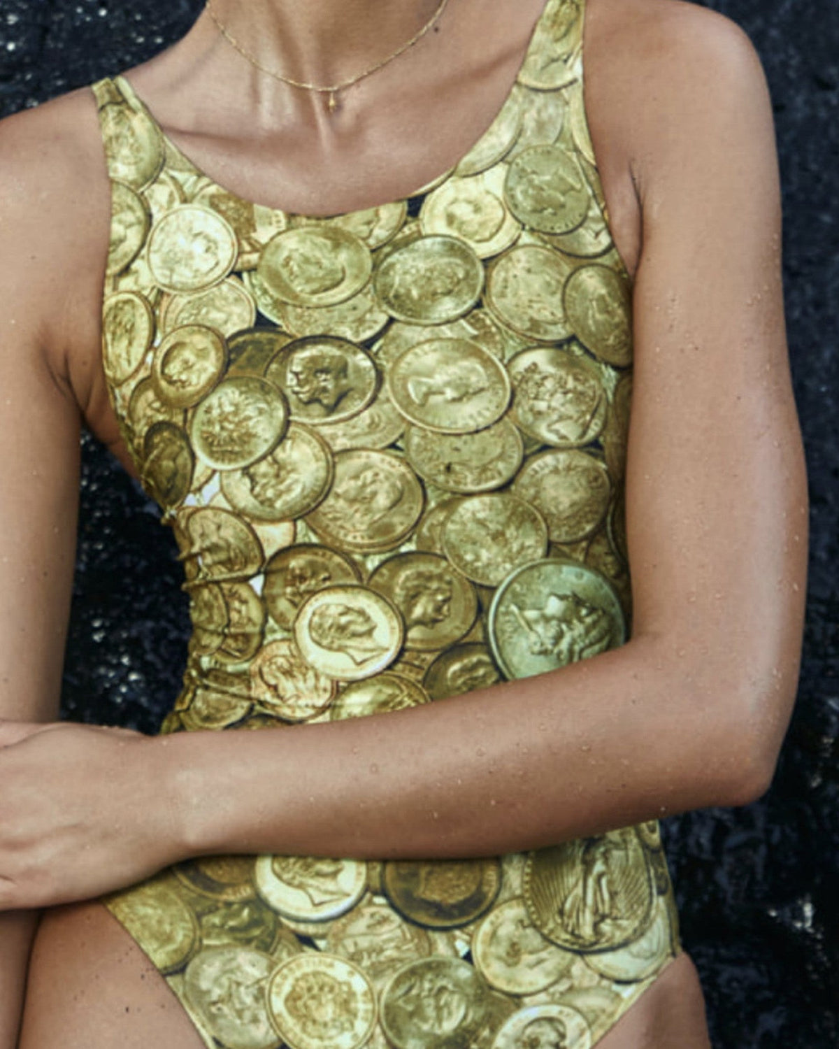 AURUM Gold Coin Print swimsuit – Gold, lifestyle shot on rocks by the water #Color_Gold