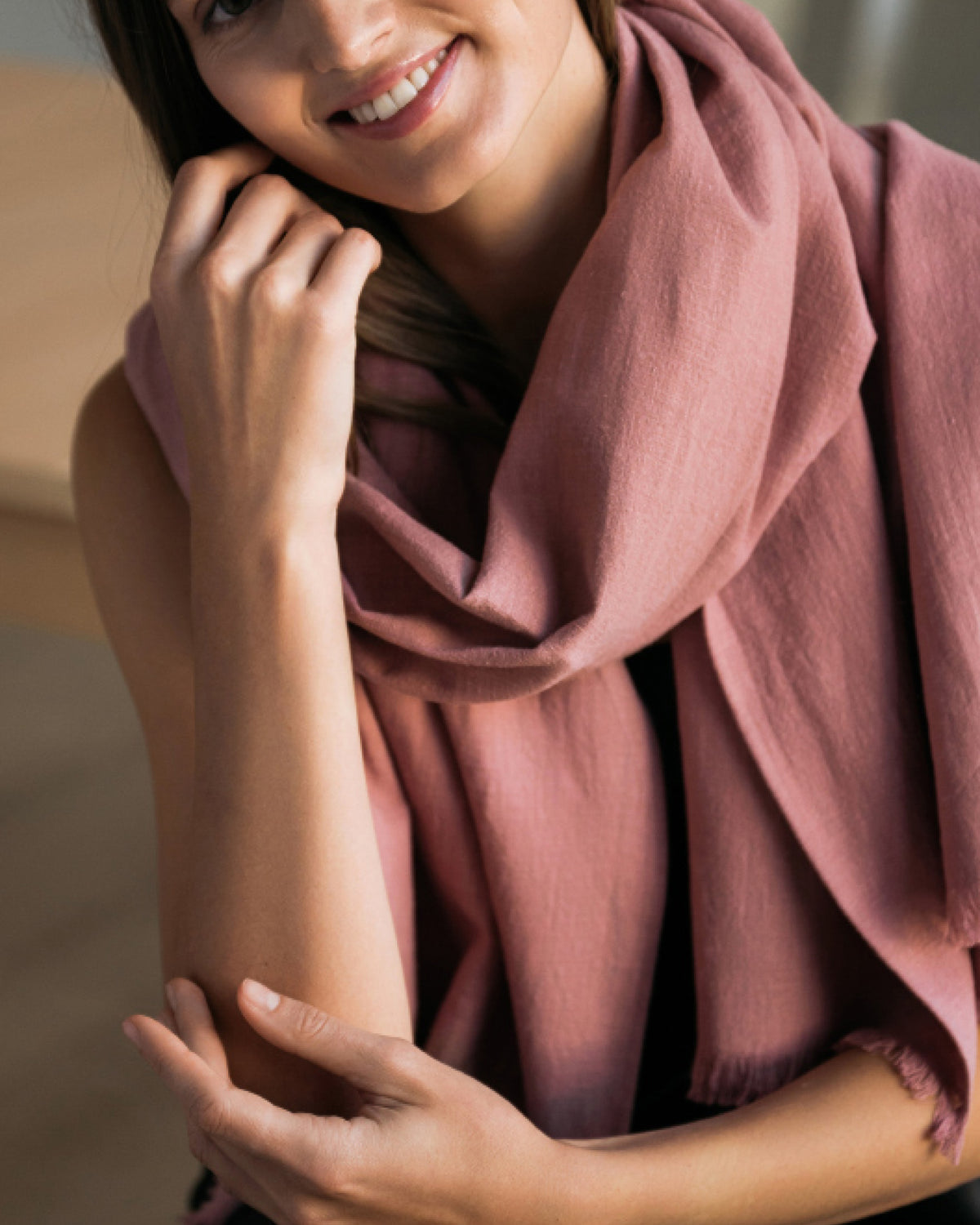 A dusty rose linen scarf worn draped around the neck, close-up lifestyle shot. #Color_Dusty rose
