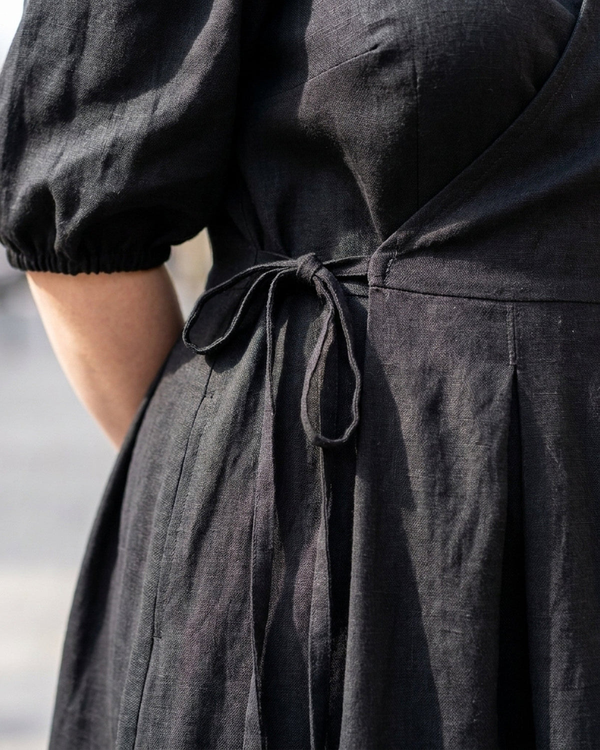 BONNIE SUPERSTAR – Linen Blend Puff Sleeve Tie-Waist Dress — Plus Size – black linen dress, close-up of the linen texture, thin waist tie and pleated skirt #Color_Black