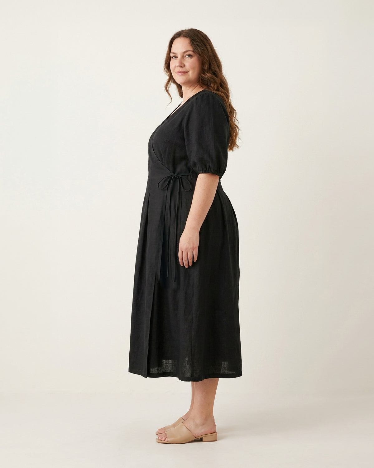 BONNIE SUPERSTAR – Linen Blend Puff Sleeve Tie-Waist Dress — Plus Size – black linen dress, full-length side view in the studio #Color_Black