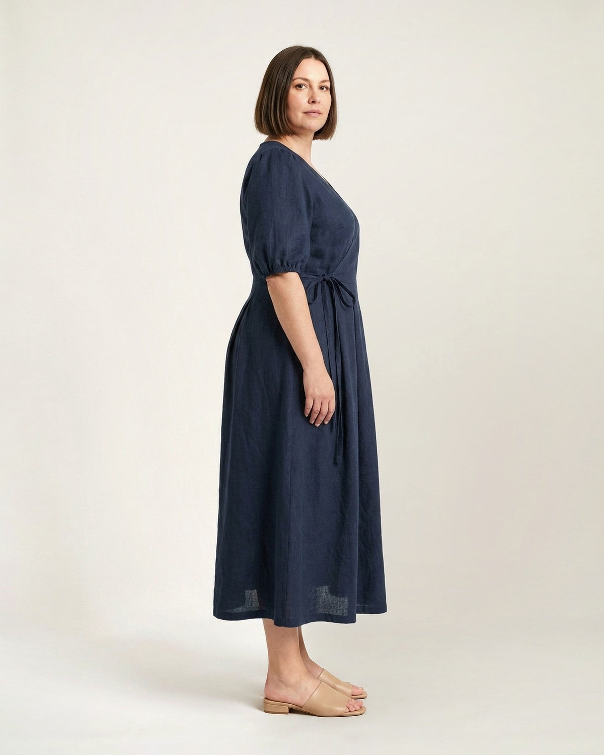 BONNIE SUPERSTAR – Linen Blend Puff Sleeve Tie-Waist Dress — Plus Size – deep blue linen dress, full-length side view in the studio #Color_Deep blue