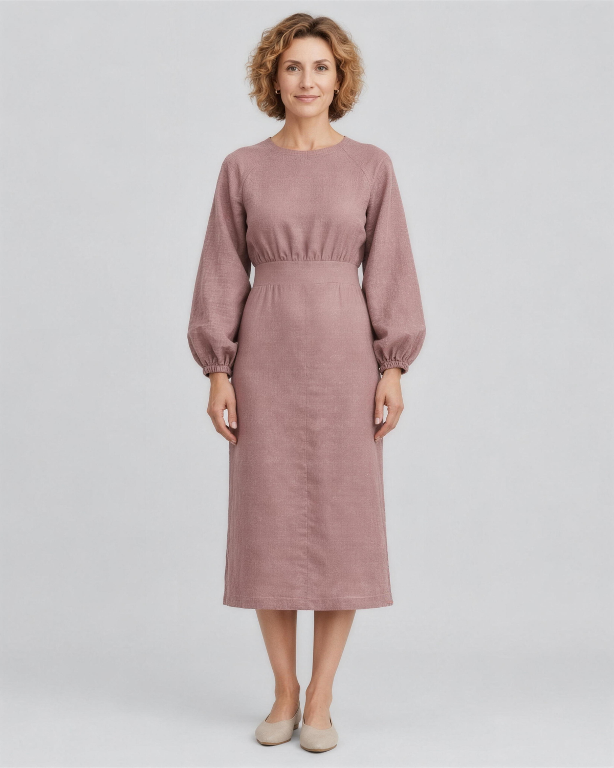 A woman standing in a studio, facing camera, full length, wearing a dusty rose linen midi dress with a gathered waist and elastic cuffs. #Color_Dusty rose