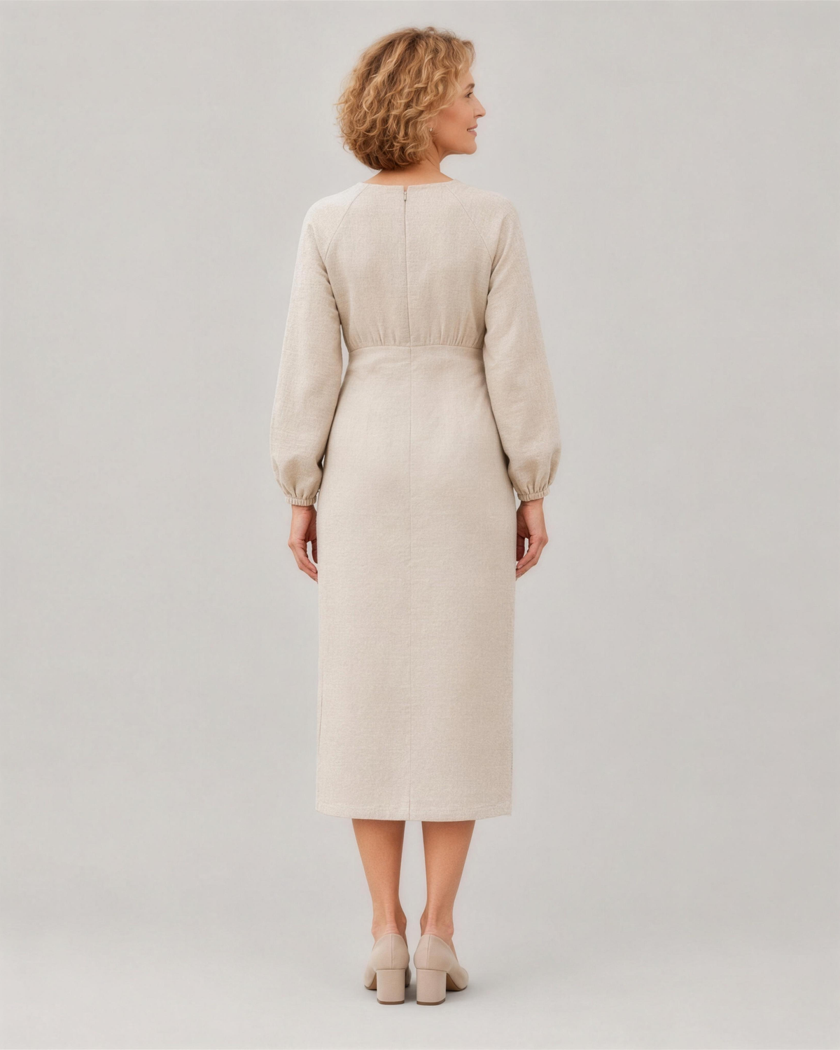A woman viewed from the back in a studio, wearing a light beige long-sleeve linen midi dress with a gathered waist, full length. #Color_Beige