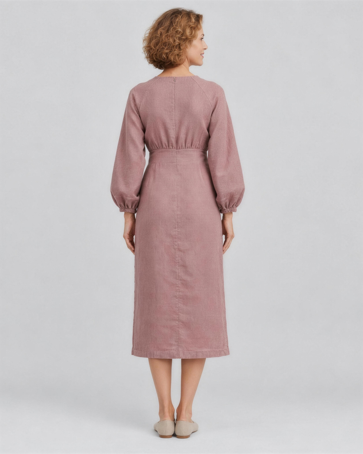 A woman viewed from the back in a studio, wearing a dusty rose linen midi dress with a gathered waist, full length. #Color_Dusty rose
