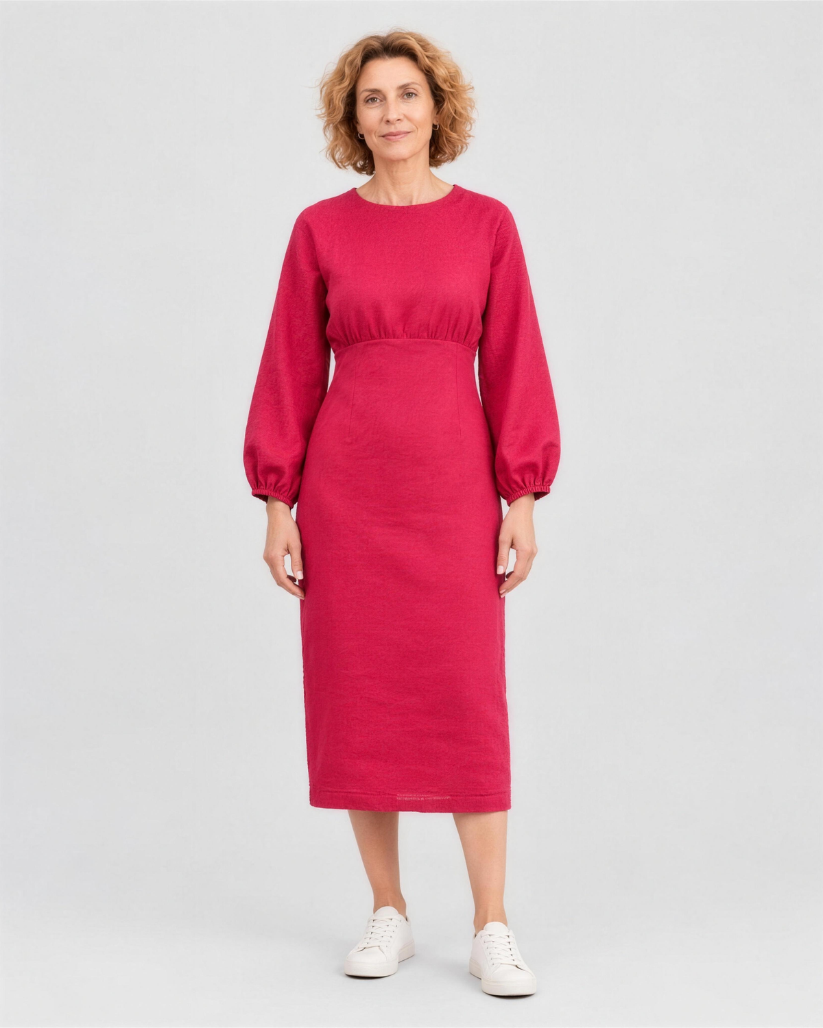 A woman standing in a studio, facing camera, full length, wearing a bright cerise red-pink linen midi dress with a gathered waist and elastic cuffs. #Color_Cerise
