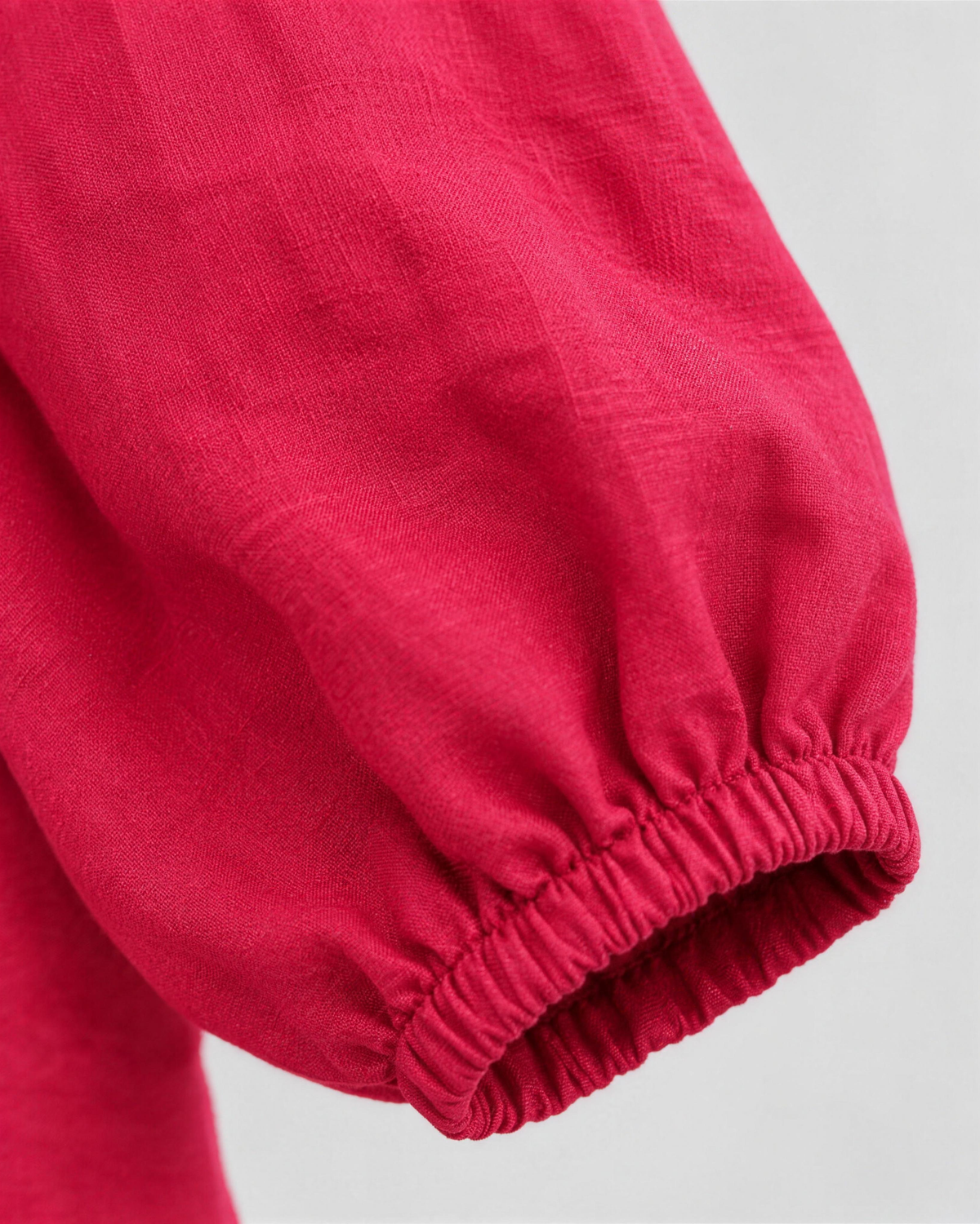 Close-up of bright cerise red-pink linen fabric texture and sleeve cuff detail on a midi dress. #Color_Cerise
