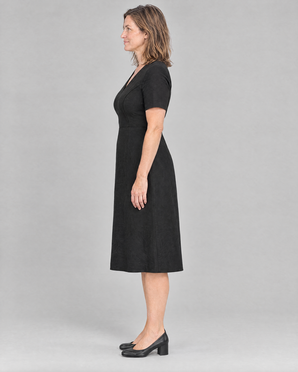 ROOM black linen midi dress, side view showing the natural waist seam and gentle A-line skirt