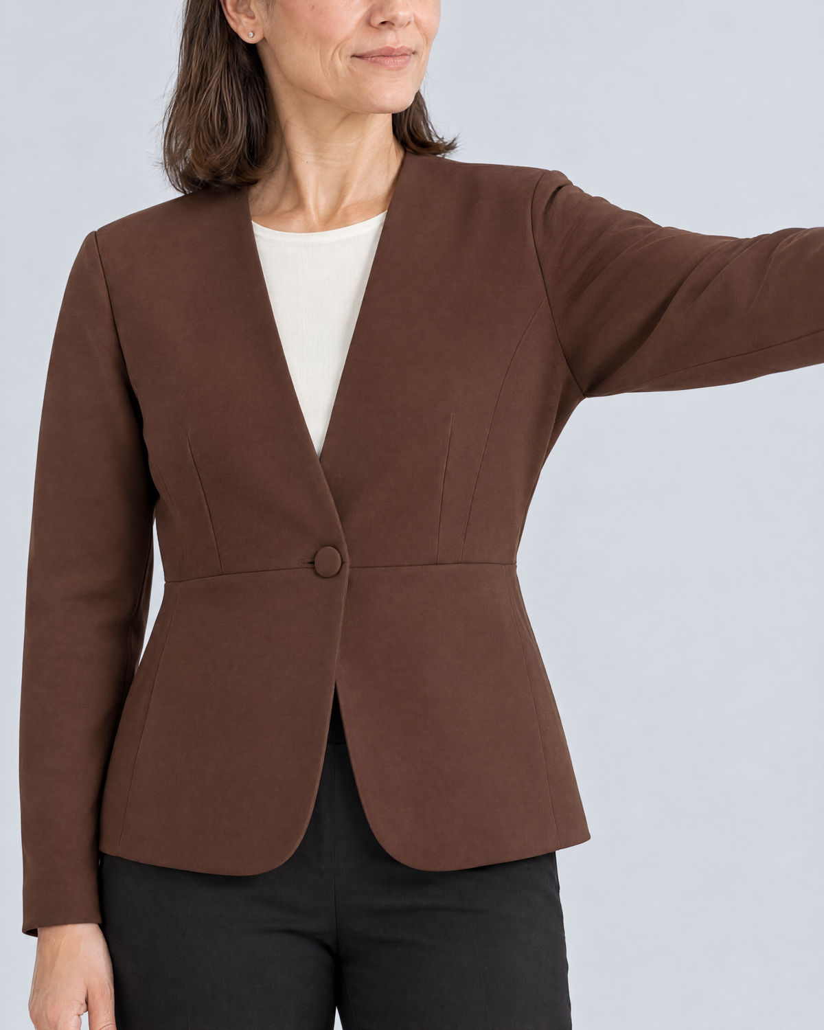 Close-up of the RIVA MOVE brown jacket with the arm raised: smooth underarm, collarless V edge and covered button