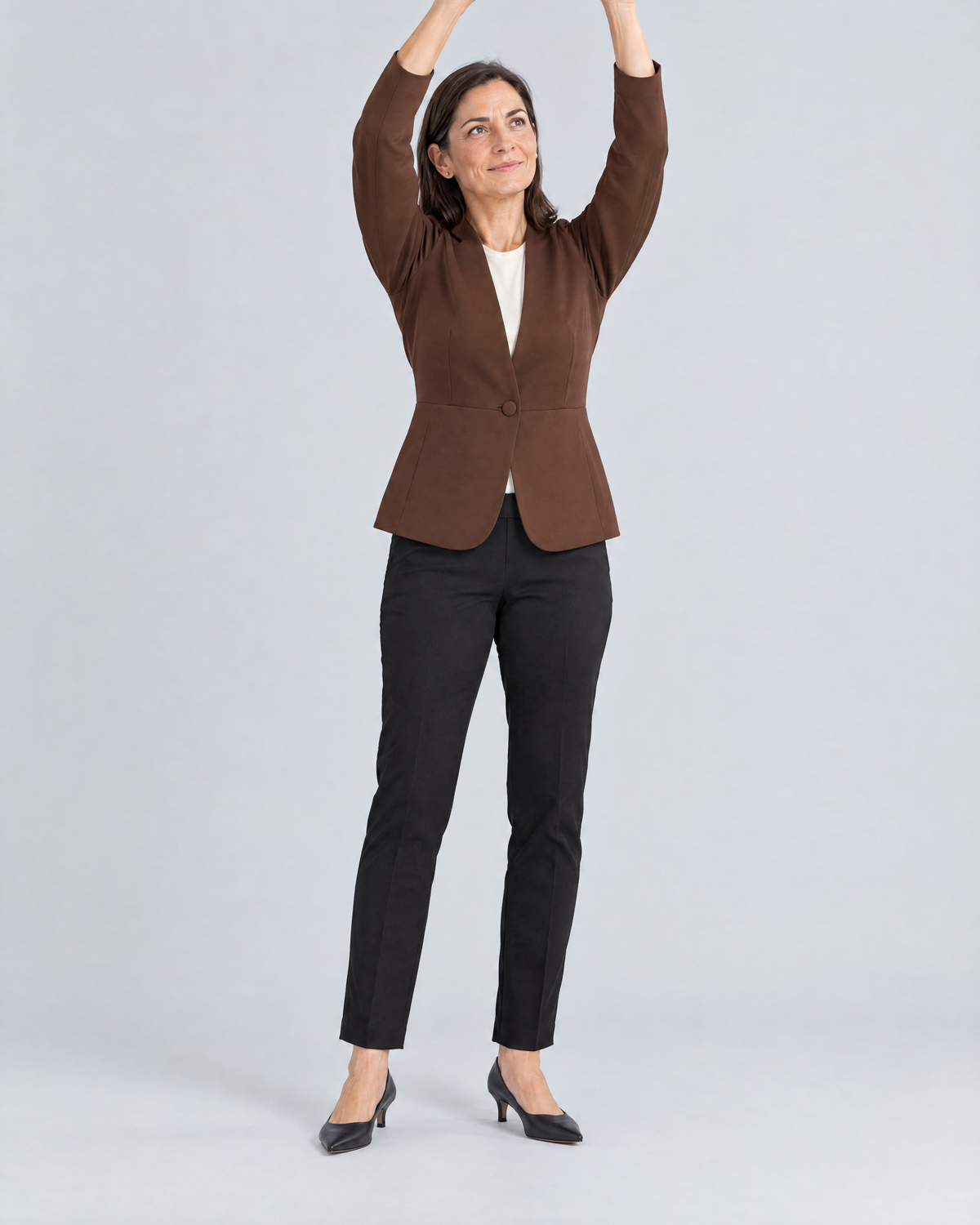Woman raising both arms in the buttoned RIVA MOVE brown jacket, the jacket stays in place