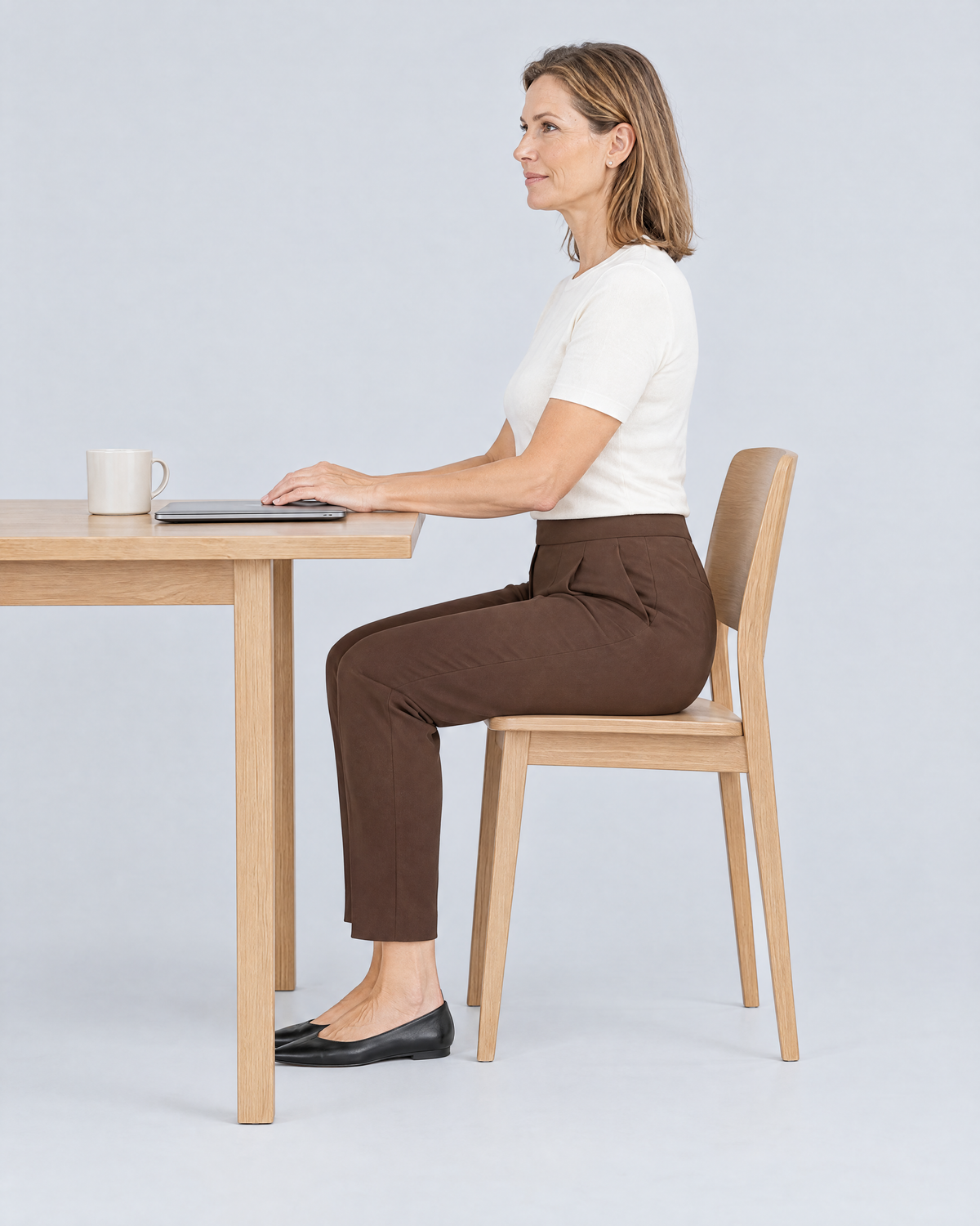 Woman sitting at a desk in SIT WELL brown trousers, the waistband stays flat and the back stays covered