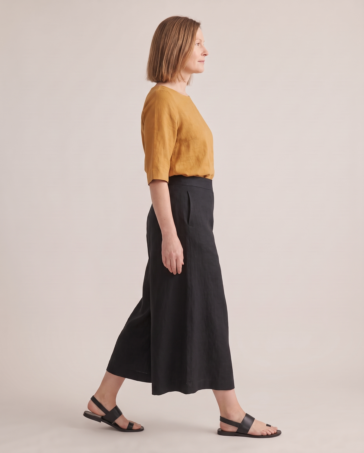 SWAY linen culottes in Black, side view mid-step showing the wide legs
