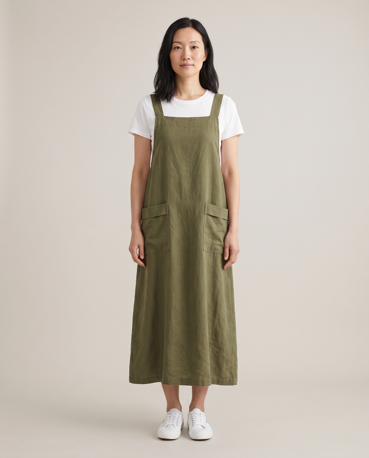 LAYER linen pinafore dress in Olive Green over a white T-shirt, front view