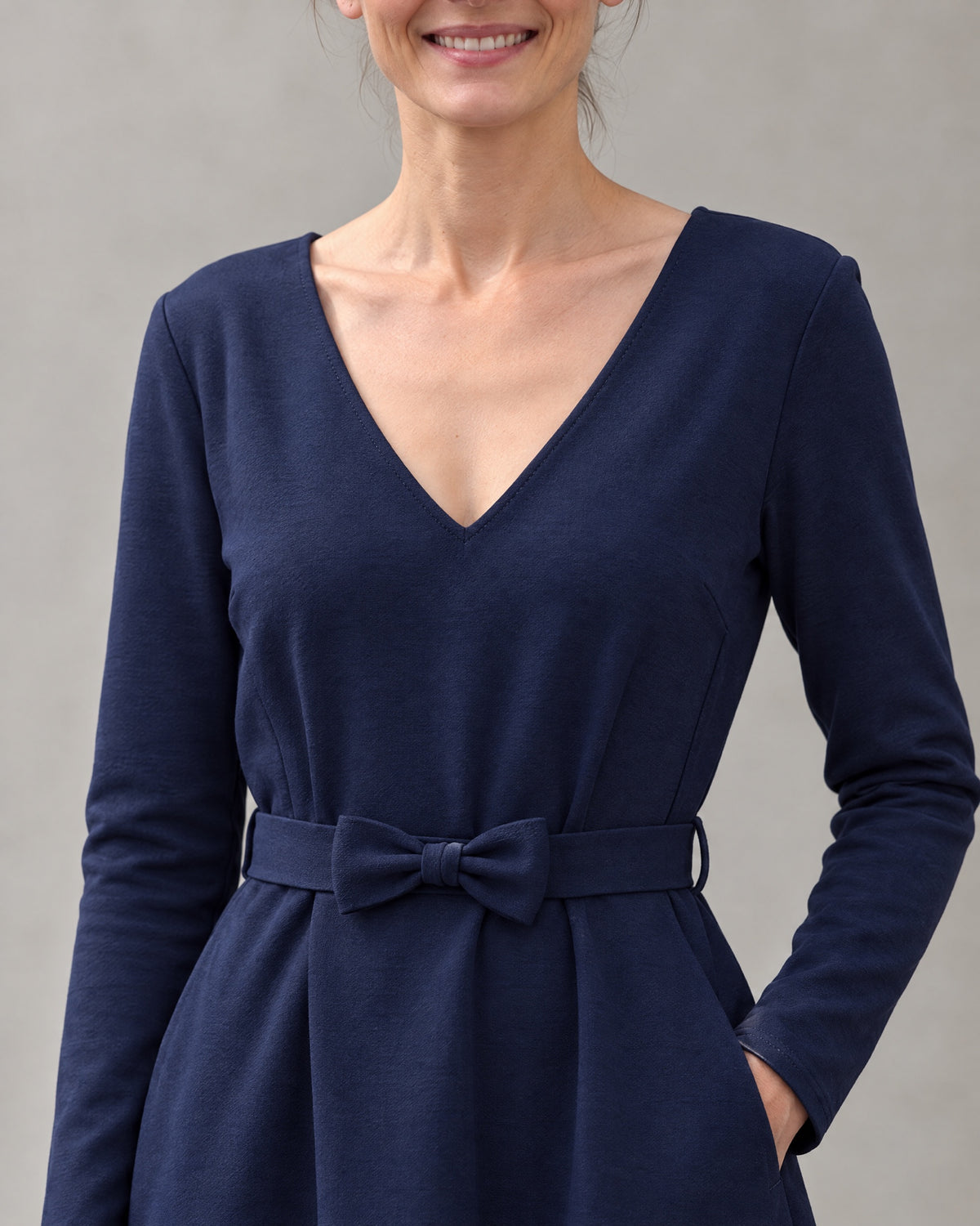 Close-up of the navy blue Punto Milano dress fabric, V-neckline and tie belt bow detail. #Color_Deep blue