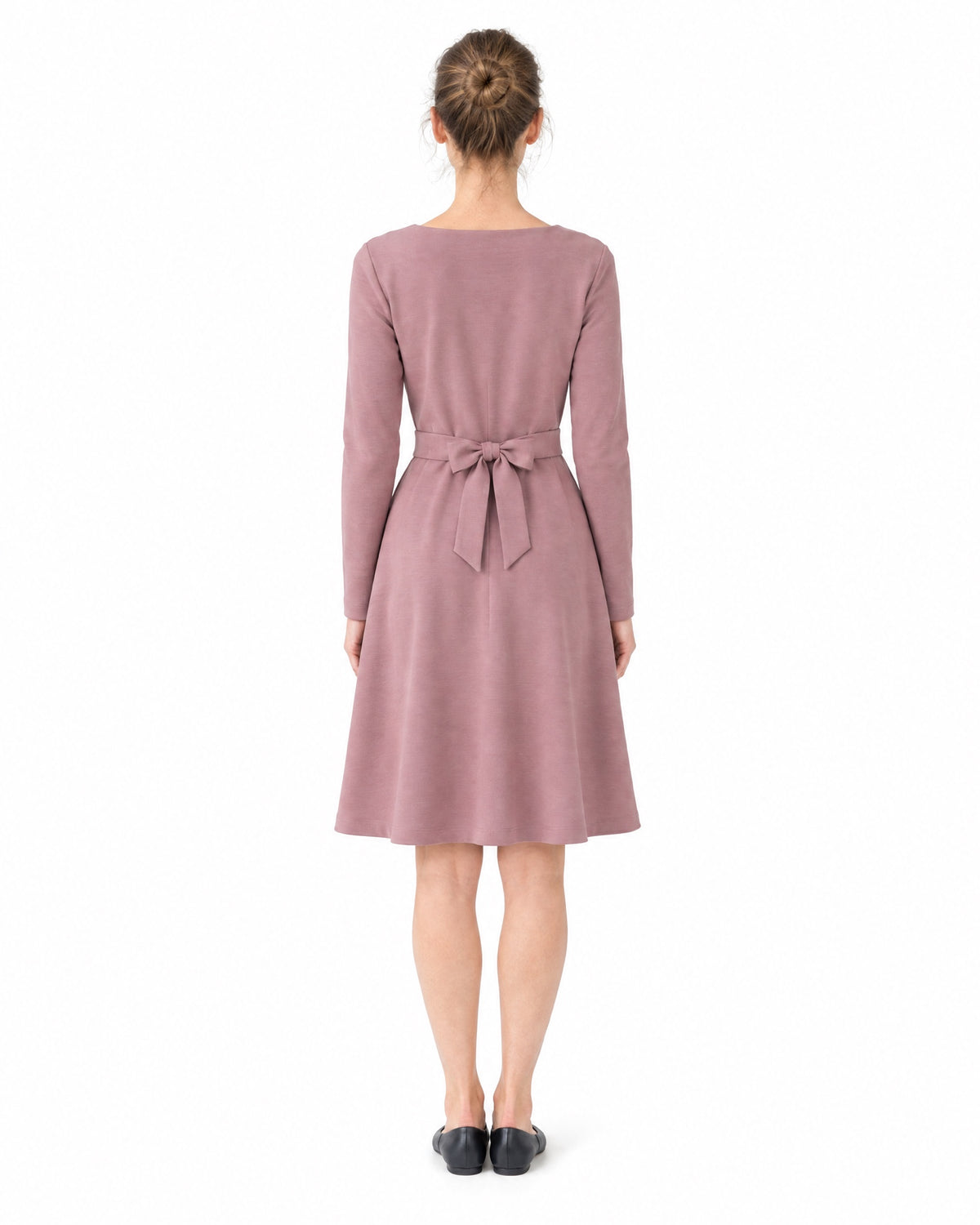 A woman wearing a dusty rose long-sleeve V-neck Punto Milano dress with a tie belt bow, back view, full length. #Color_Dusty rose