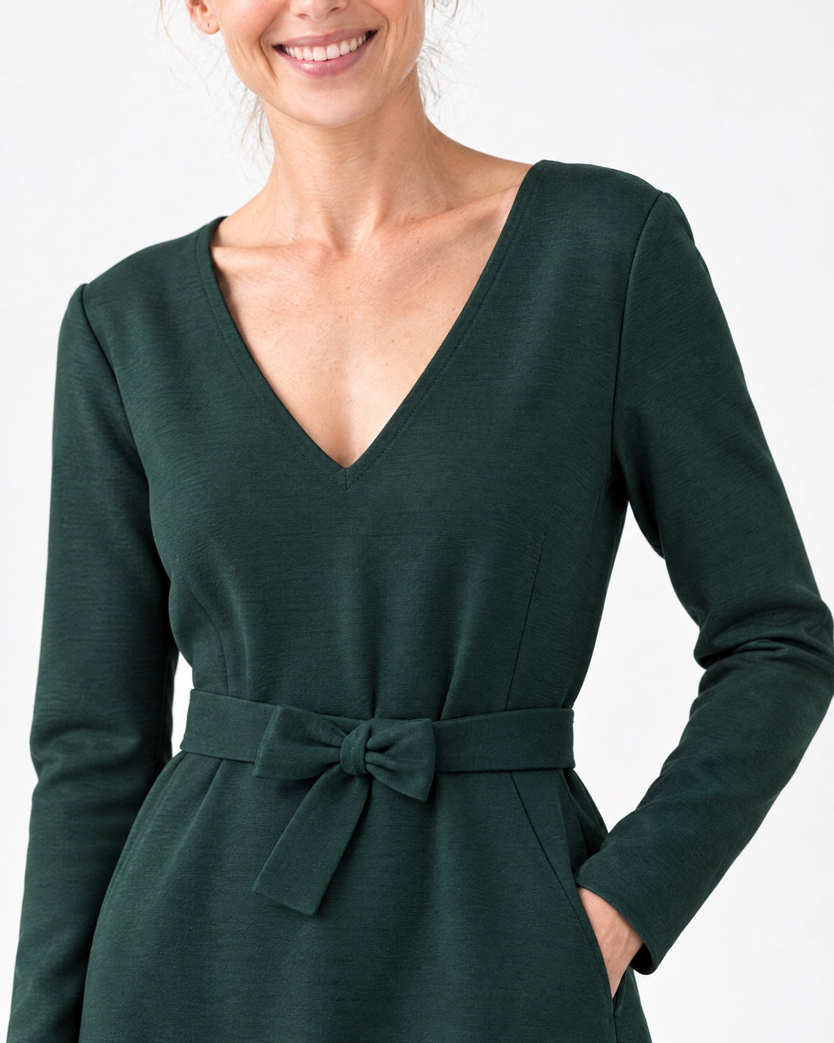 Close-up of the dark green Punto Milano dress fabric, V-neckline and tie belt bow detail. #Color_Green