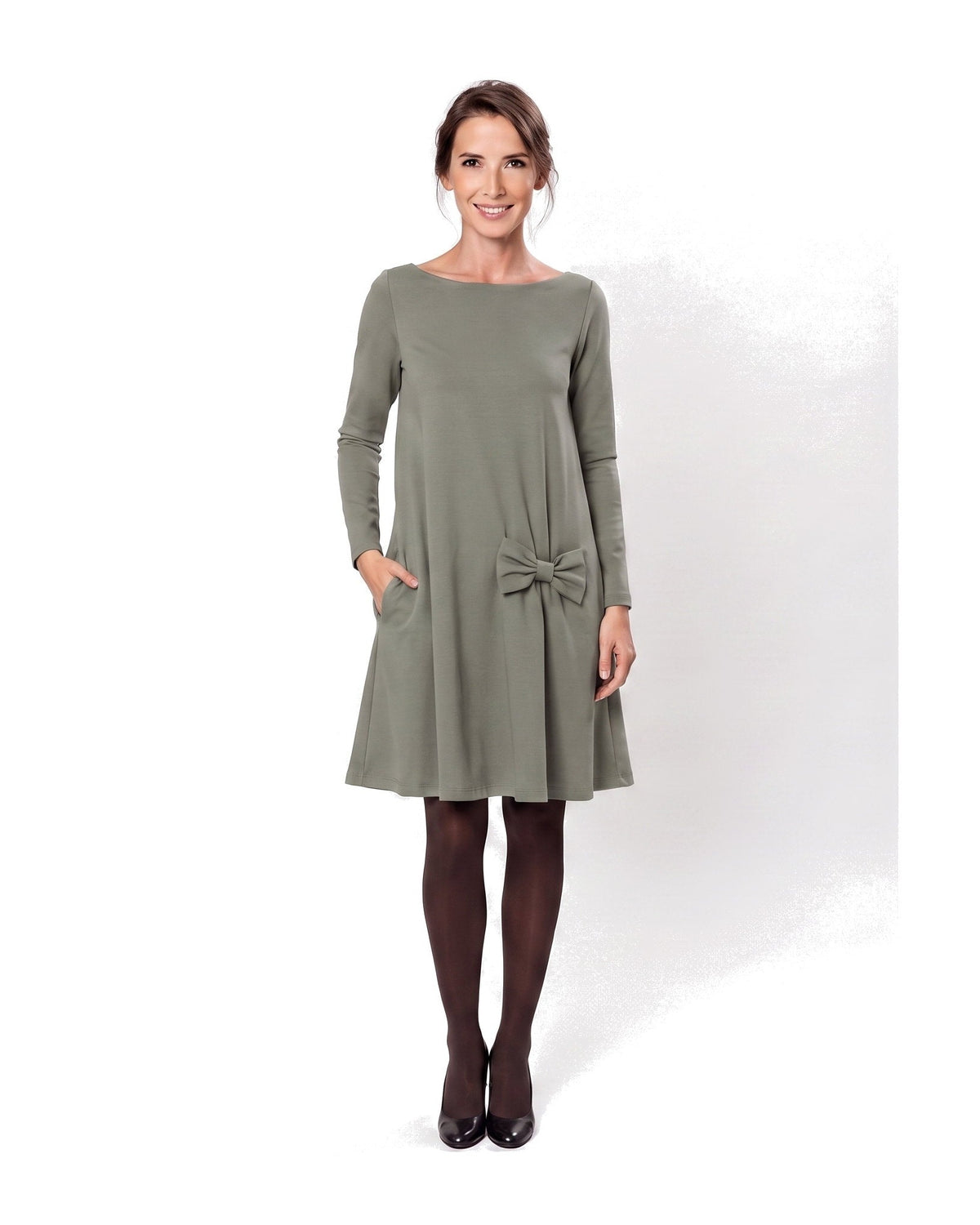 A woman modeling a olive green long-sleeve A-line dress with a boat neckline, side pockets, and a bow detail at the waist. #Color_Gray green
