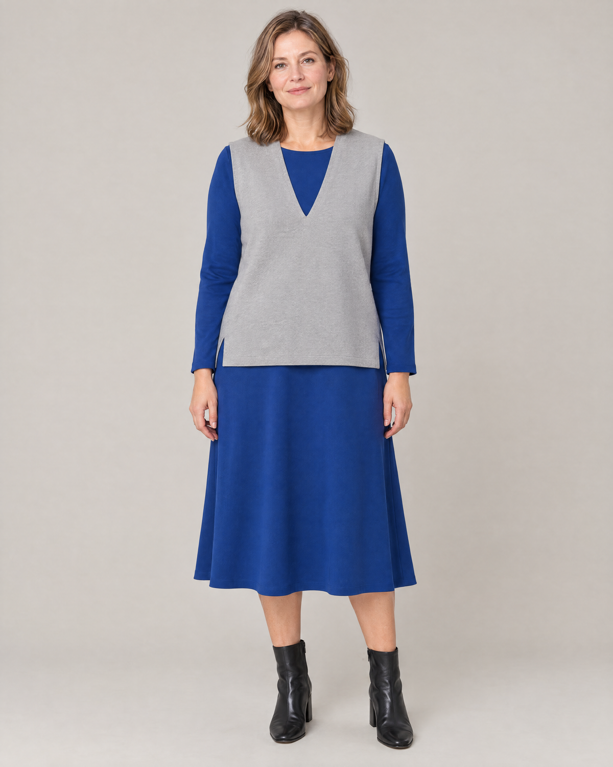 LIGHT VEST in light grey fine wool, sleeveless with a deep V-neck, worn over a cobalt blue midi dress, front view