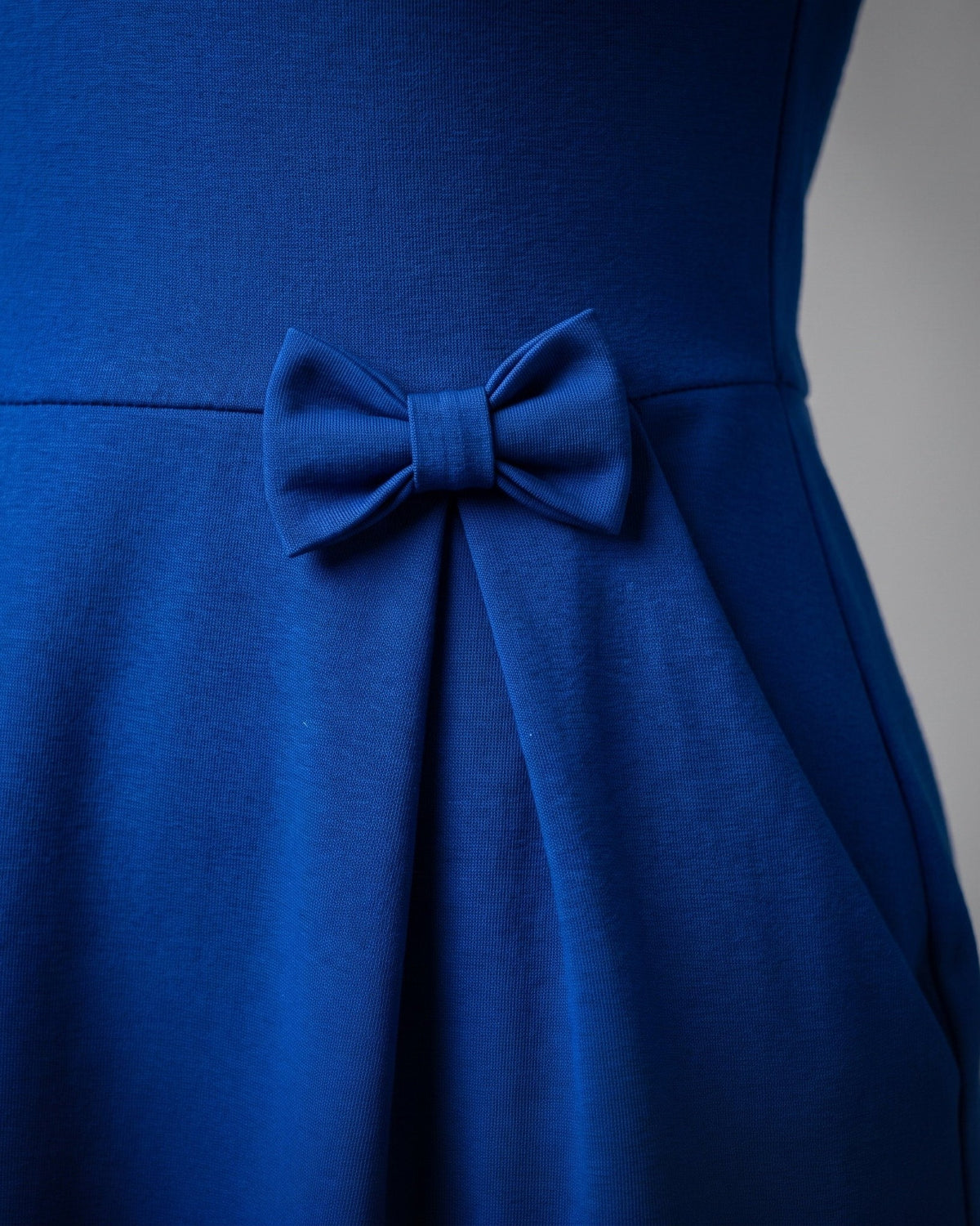 Close-up of the fabric bow detail at the waist of the MADMUAZEL sapphire blue Punto Milano dress #Color_Sapphire blue
