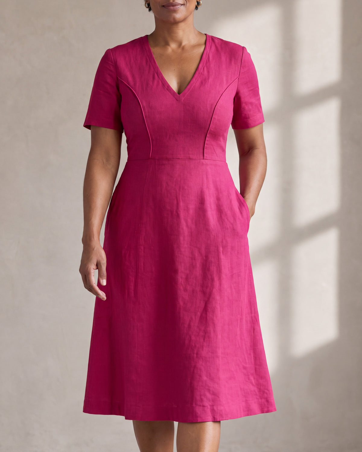 ROOM cerise Dutch linen V-neck A-line midi dress with piped princess seams and side-seam pockets, close front view