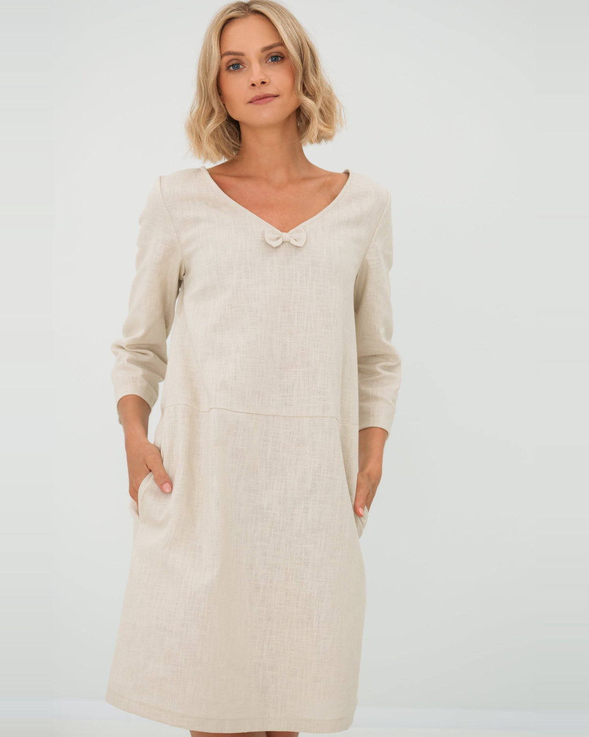 SUN – Linen Blend V-Neck Bow Dress – Beige dress, front view, hands in pockets, studio #Color_Beige