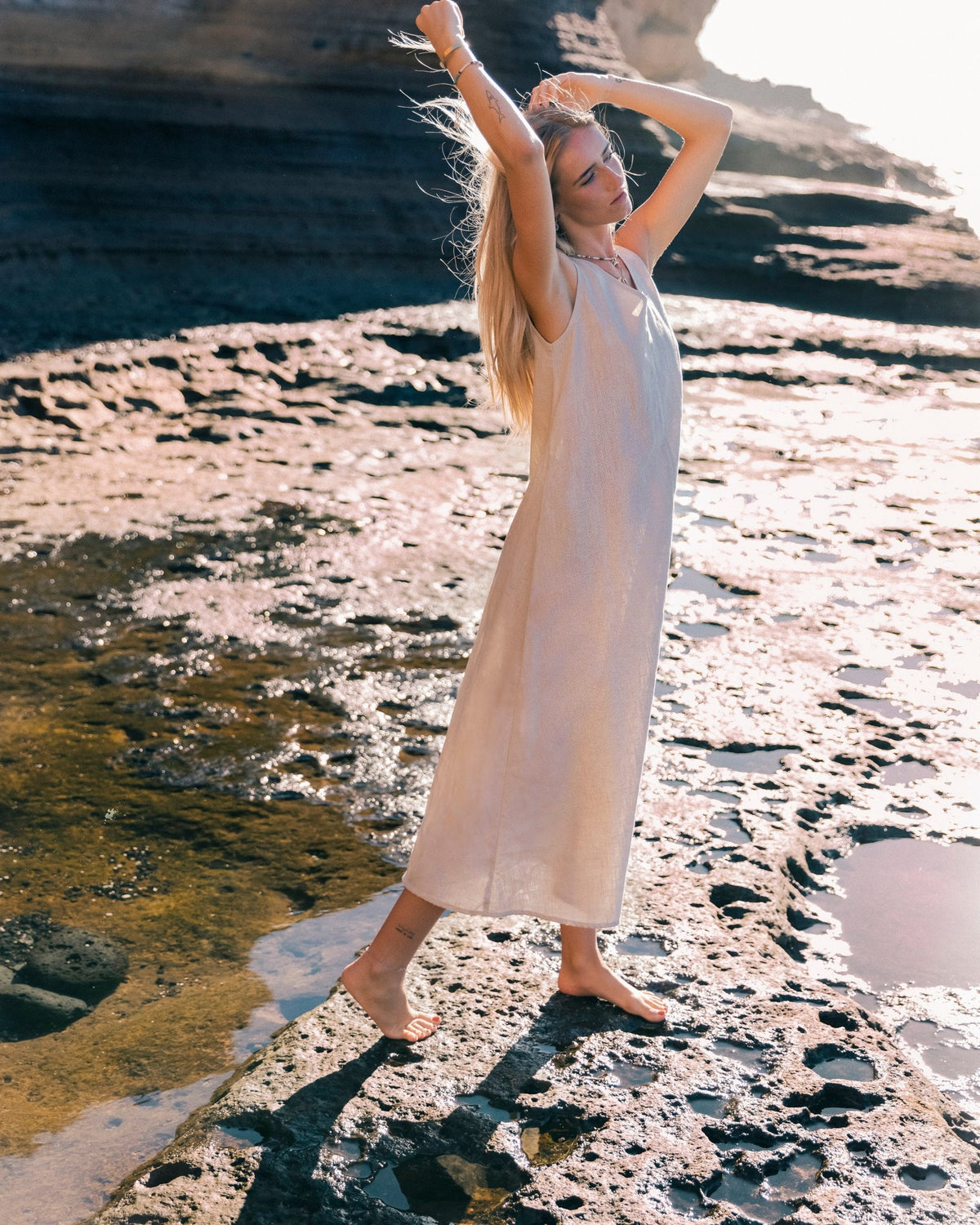 LeMuse SUNSET linen dress in beige – model in motion with arm raised #Color_Beige