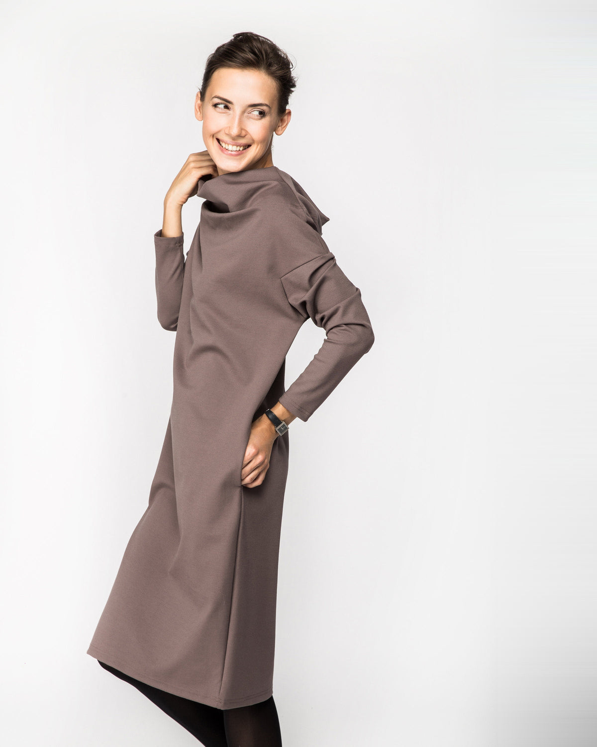 A woman wearing a taupe brown long-sleeve cowl-neck midi dress with side pockets, side profile view. #Color_Cacao